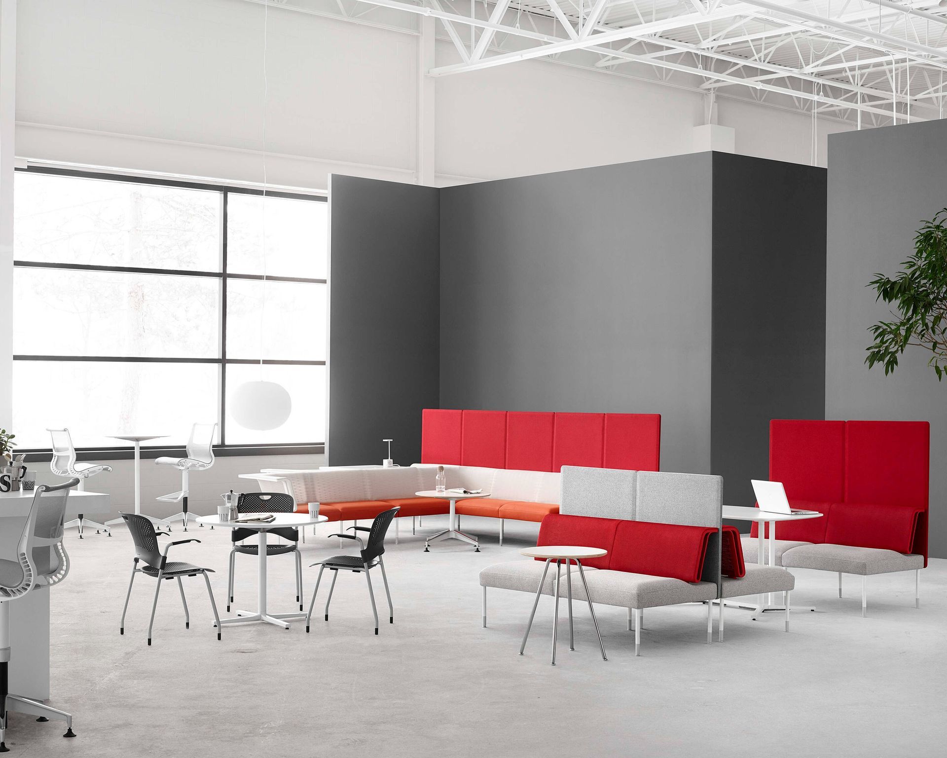 Modern lounge with red sofas, white tables, and chairs in a bright open office space
