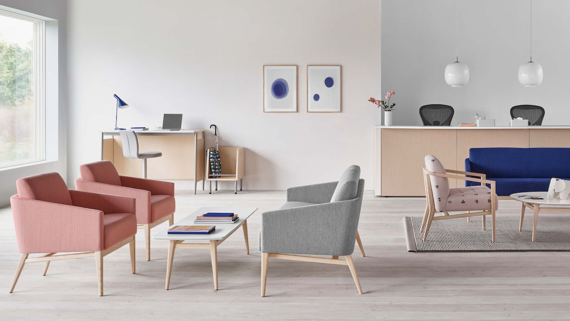 Modern living room with pink and gray chairs, a blue sofa, and minimalist decor.