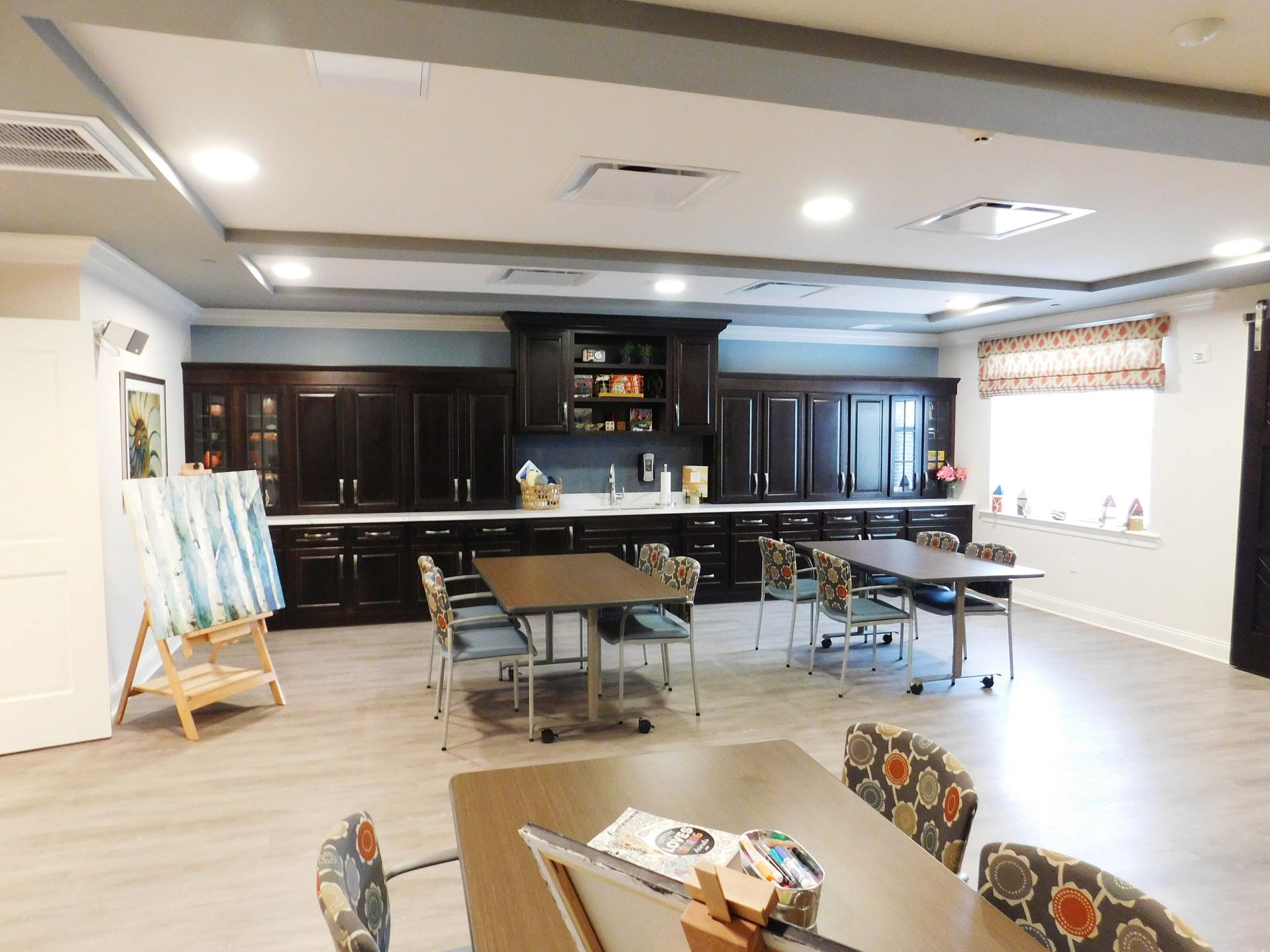 Spacious meeting room with tables, chairs, cabinets, and bright overhead lighting