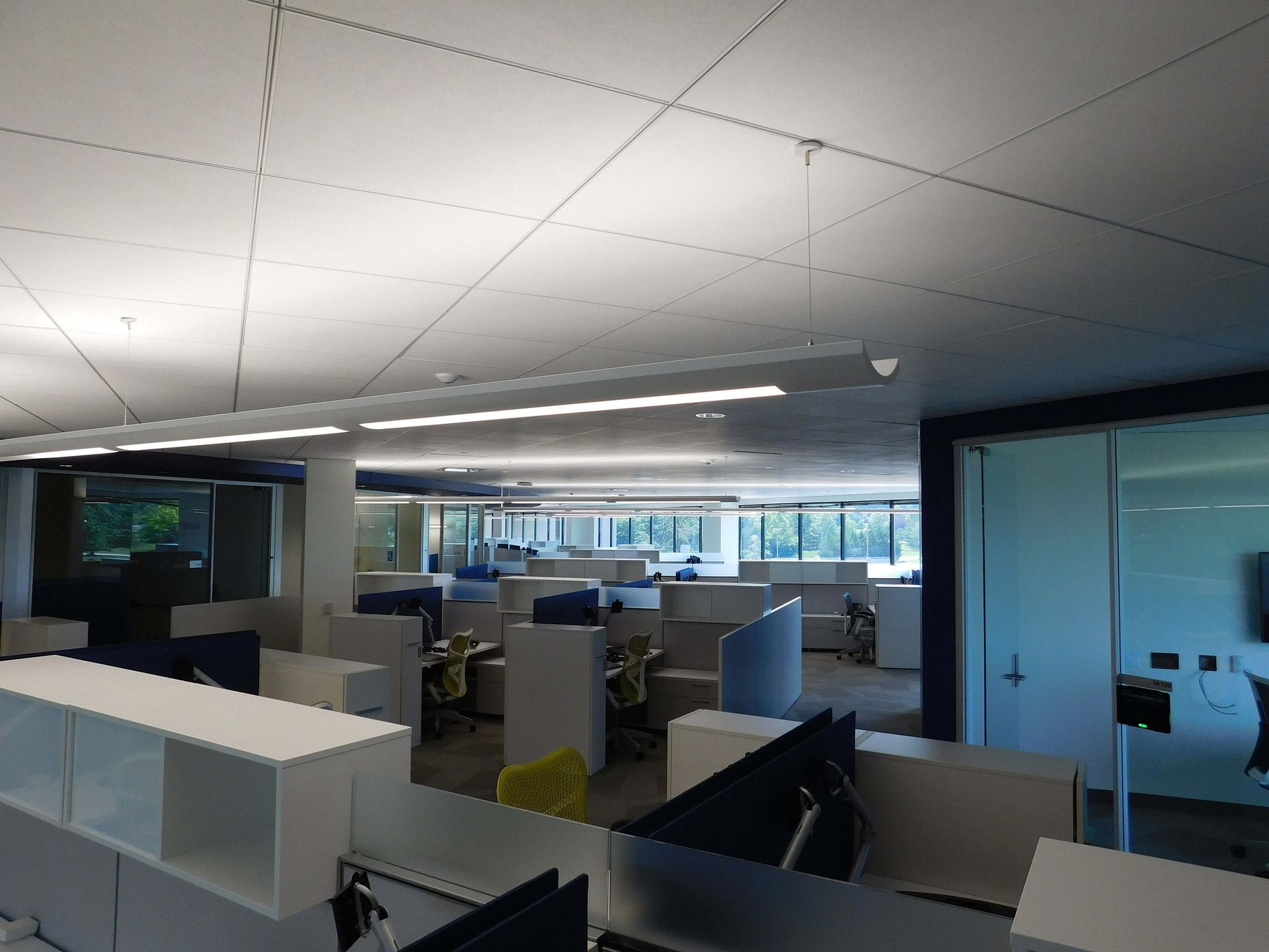 Empty office interior with desks, computers, and ceiling lights