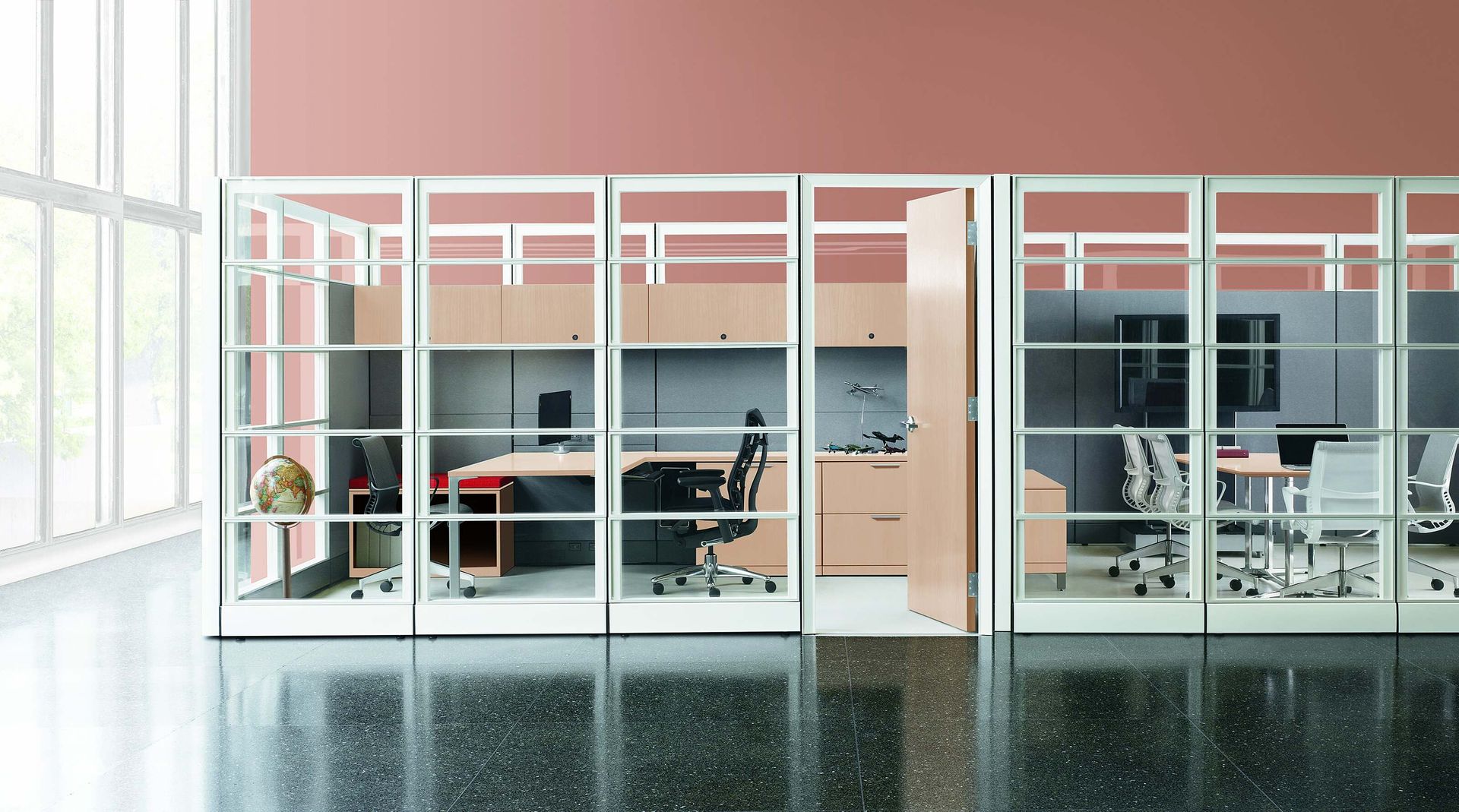 Modern office interior with glass walls, desks, chairs, and large windows in a pink-walled room