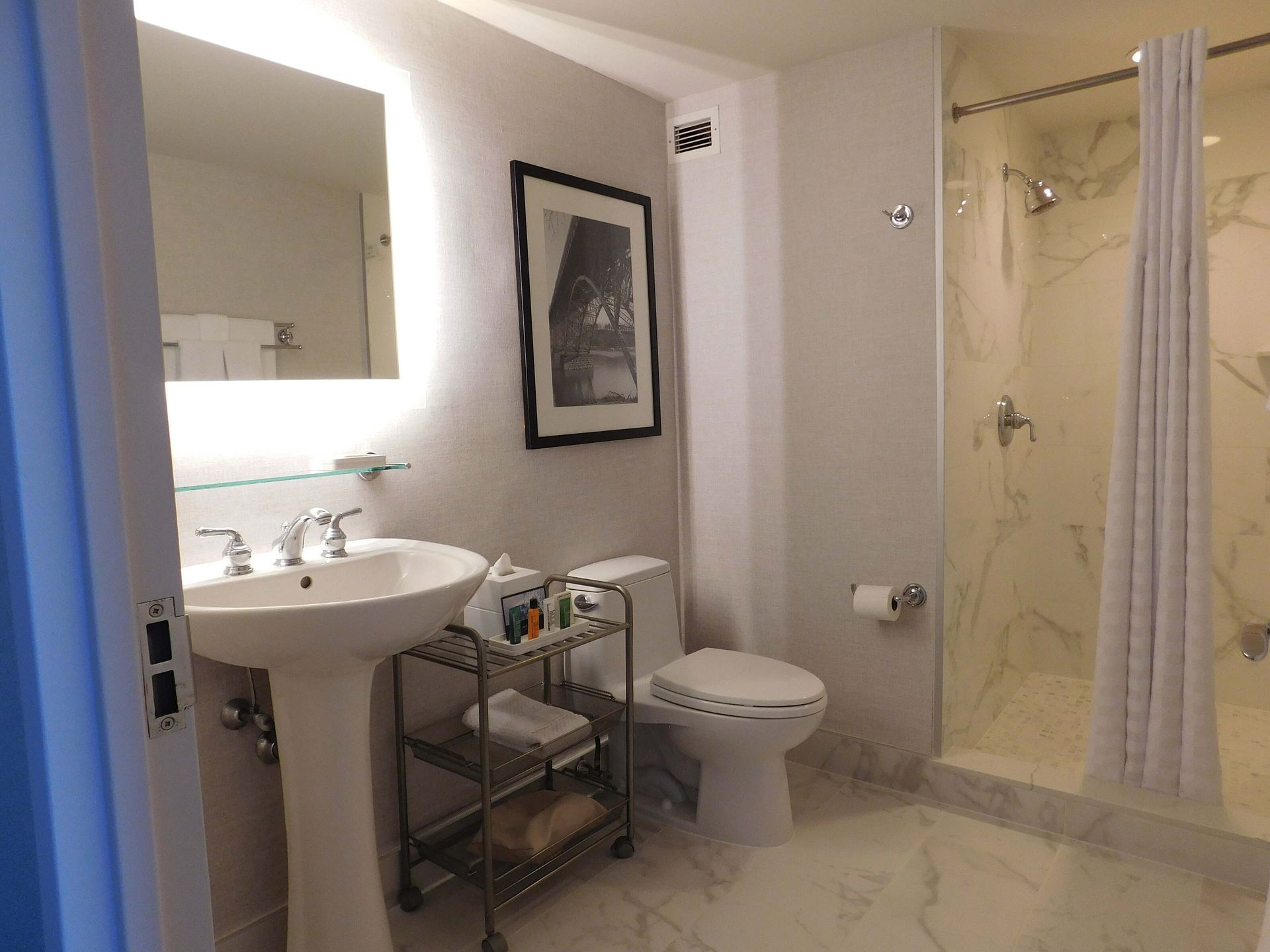 Small bathroom with sink, toilet, framed art, and a bathtub with a shower curtain.