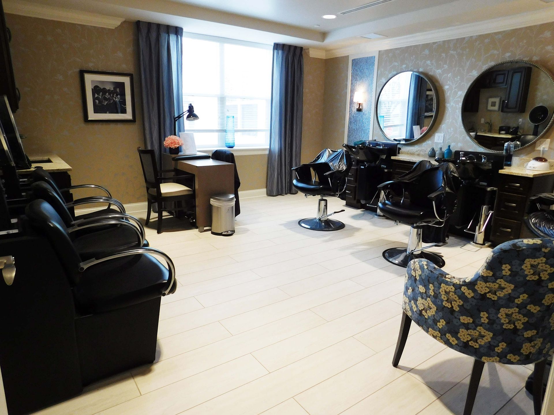 Modern hair salon with black chairs, mirrors, and a large window letting in daylight