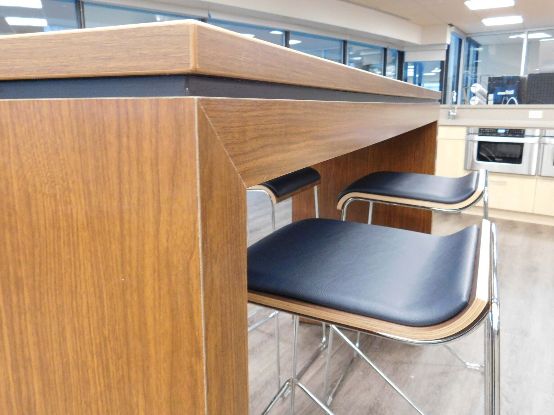 Wooden table with built-in black stools in a bright modern kitchen or café area