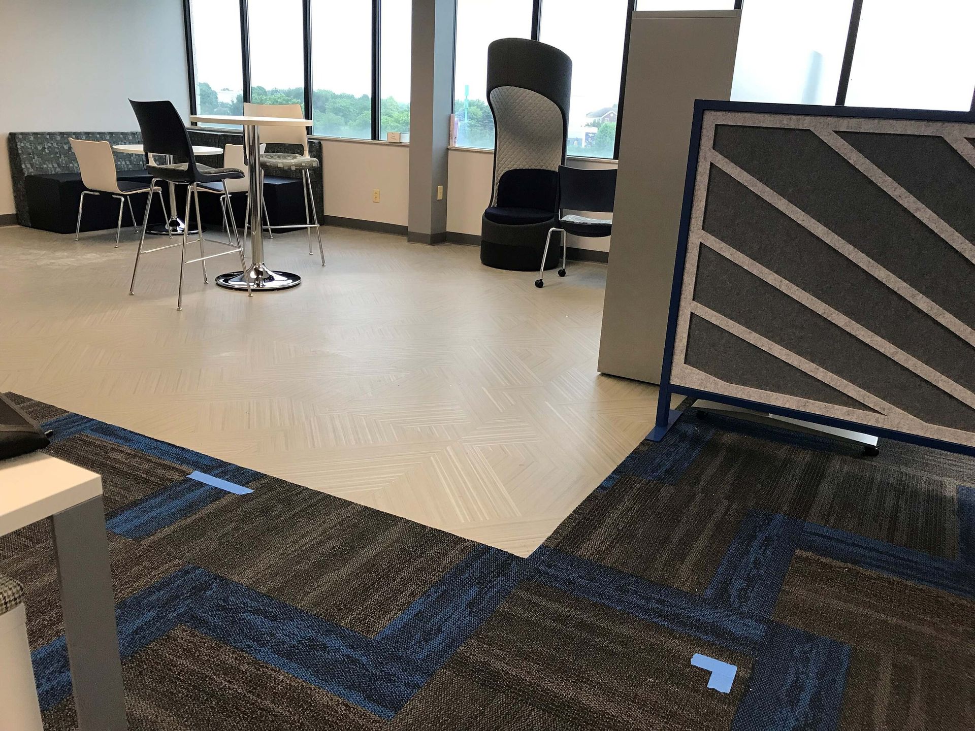 Empty room with chairs, tables, and a tiled floor near large windows