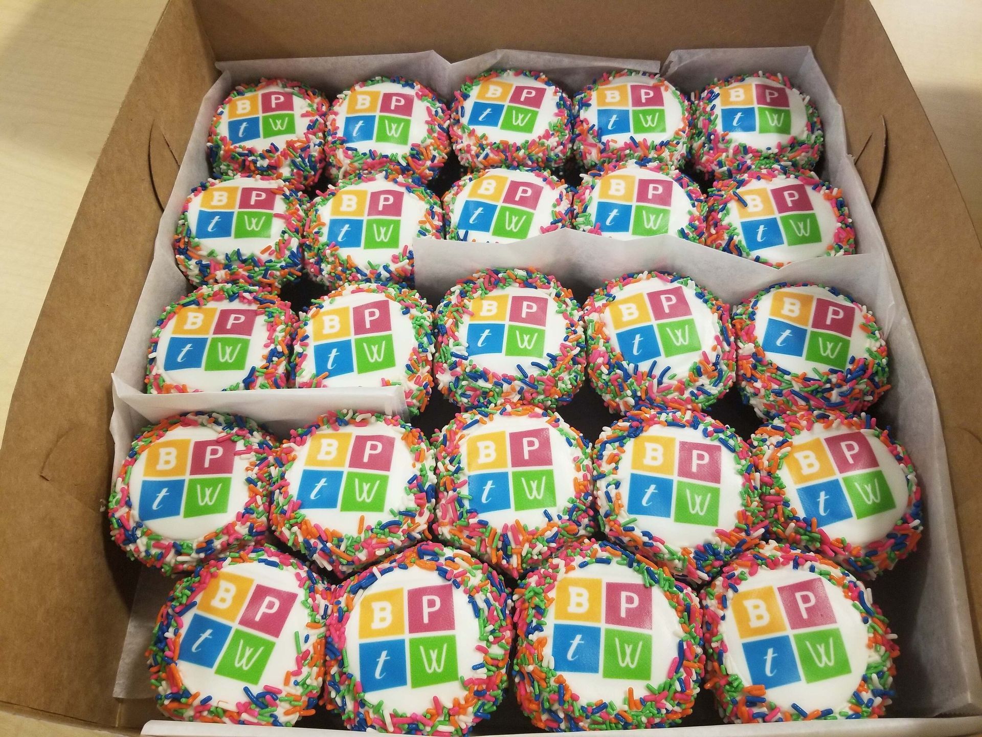 Box of colorful wrapped cupcakes with alphabet blocks printed on the wrappers