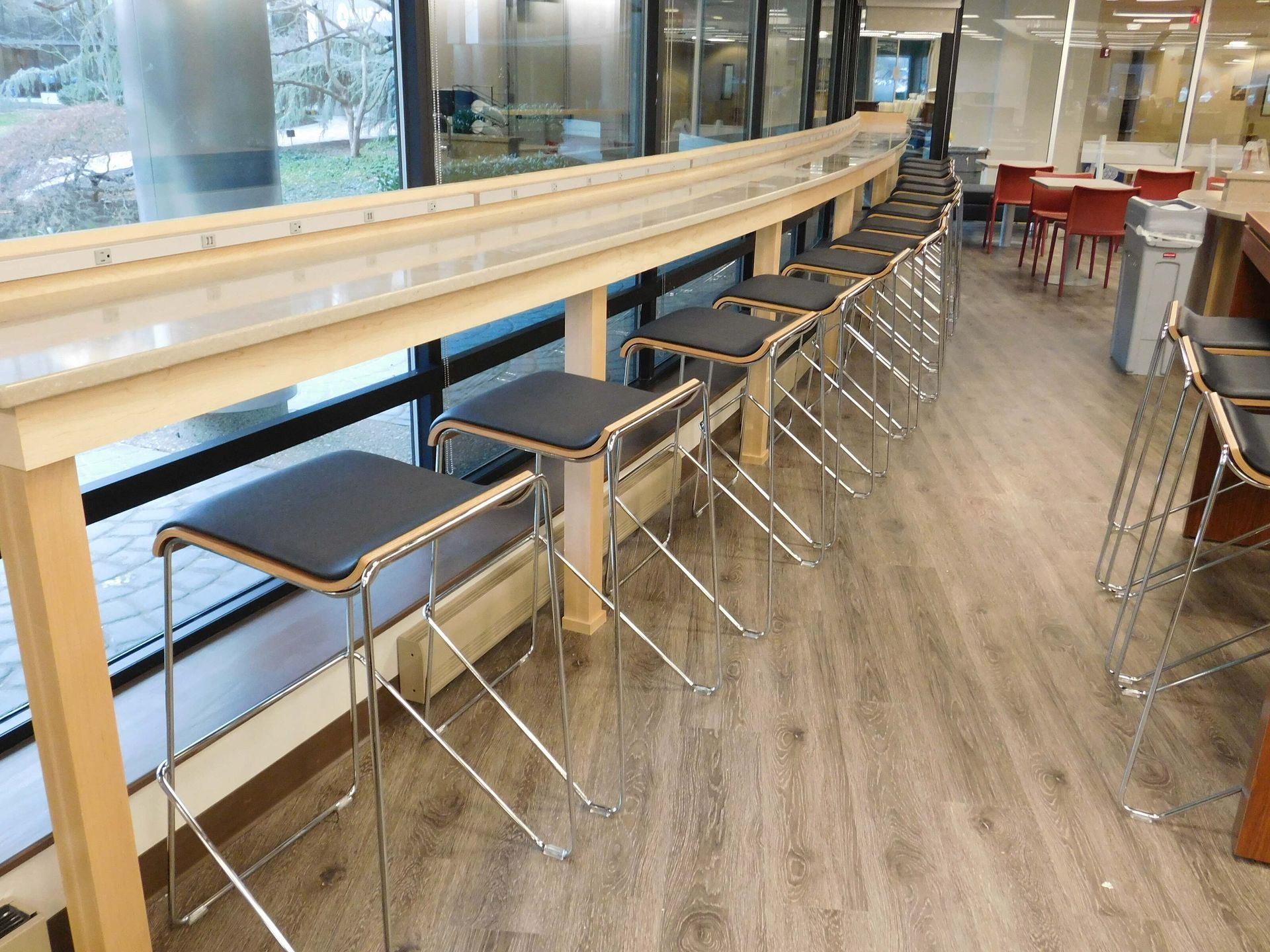 Empty modern café with a long wooden counter and stools by large windows
