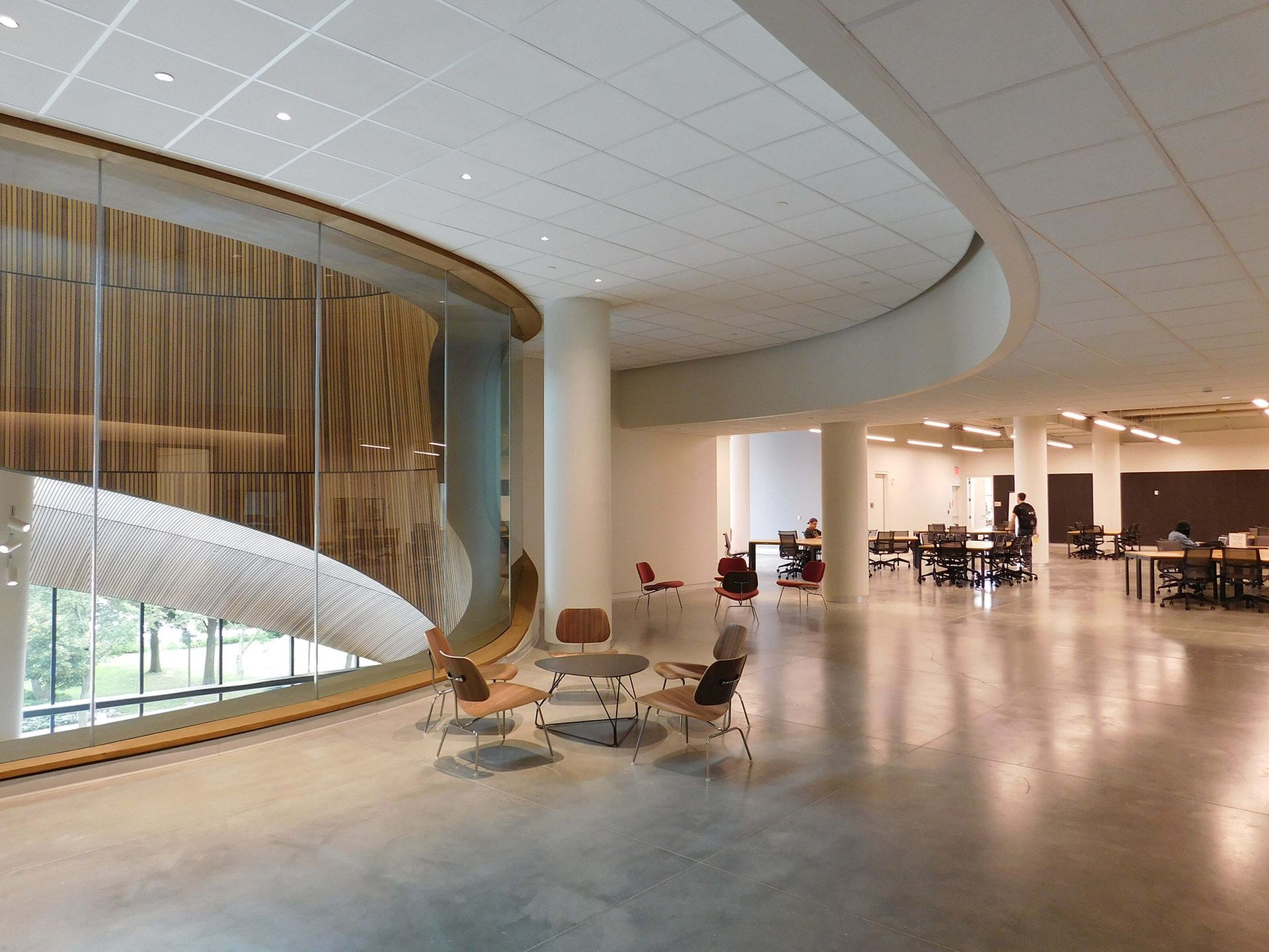 Modern lobby with curved glass wall, lounge chairs, and polished floor in a spacious interior