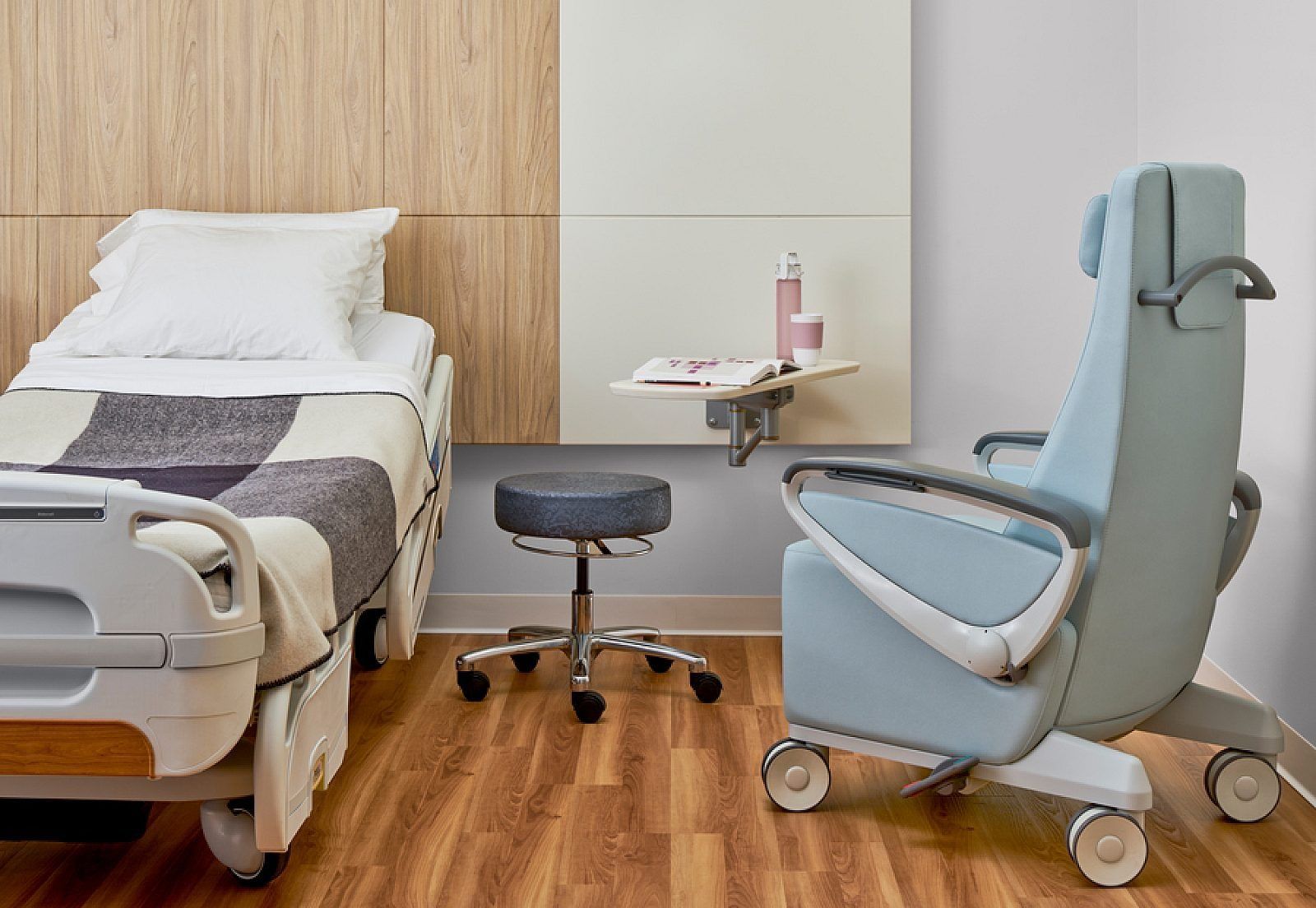 Light gray wheelchair with padded backrest, armrests, leg rest, and small caster wheels