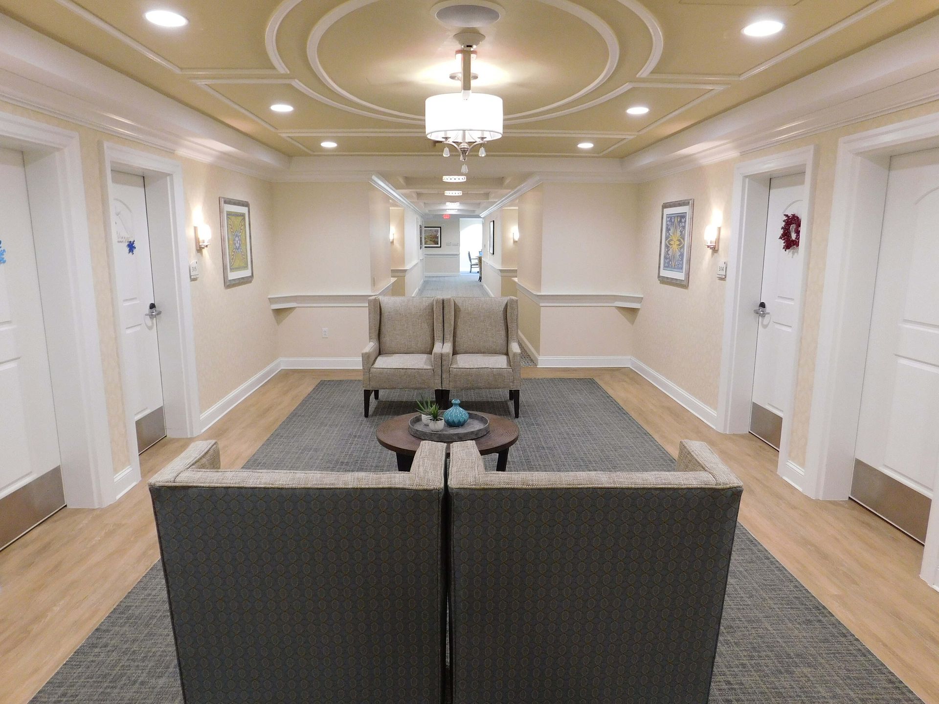 Elegant hotel hallway with beige seating, chandelier lighting, and patterned carpet