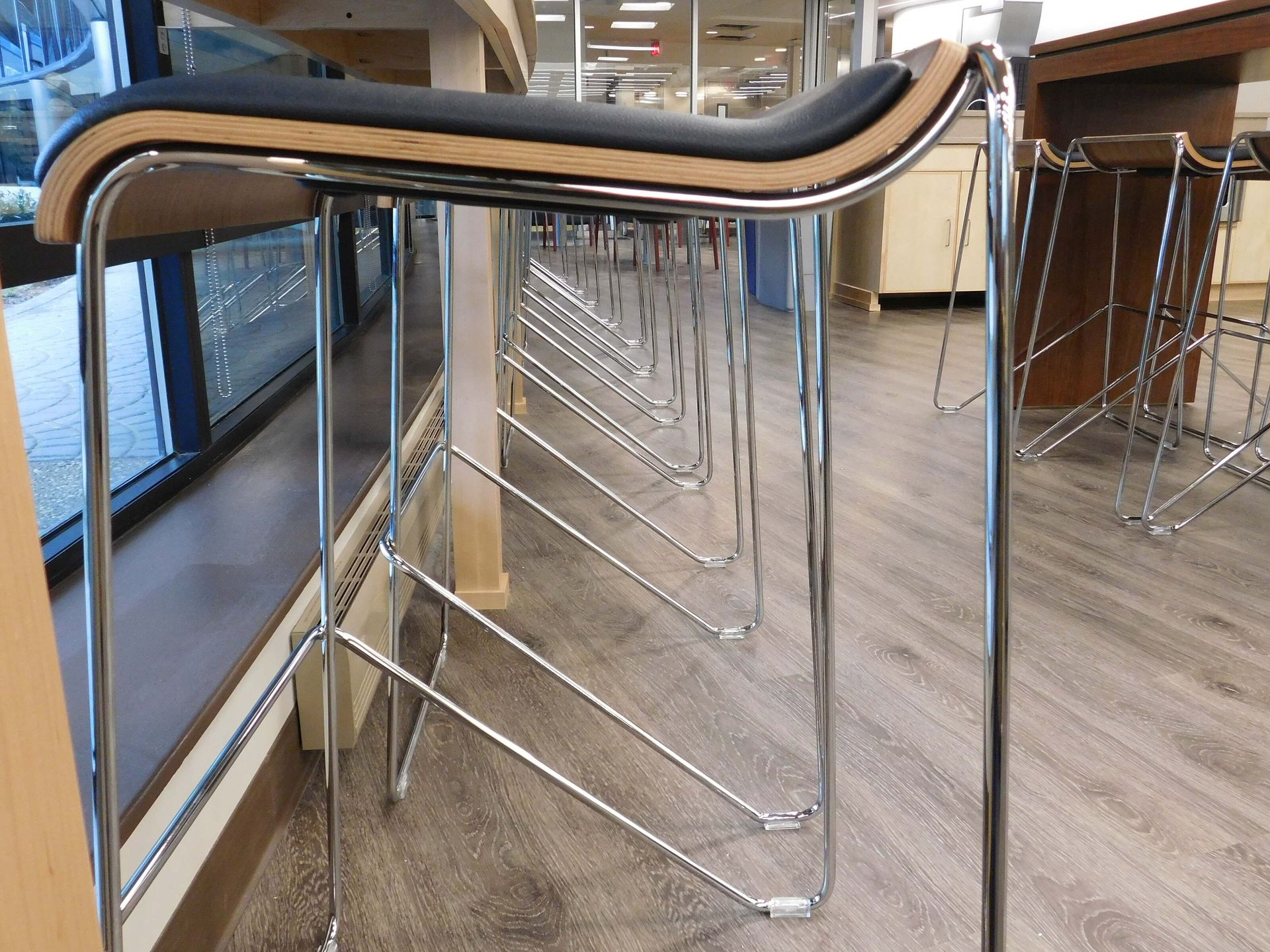 Metal queue barriers in a bright indoor lobby with wood flooring and glass doors