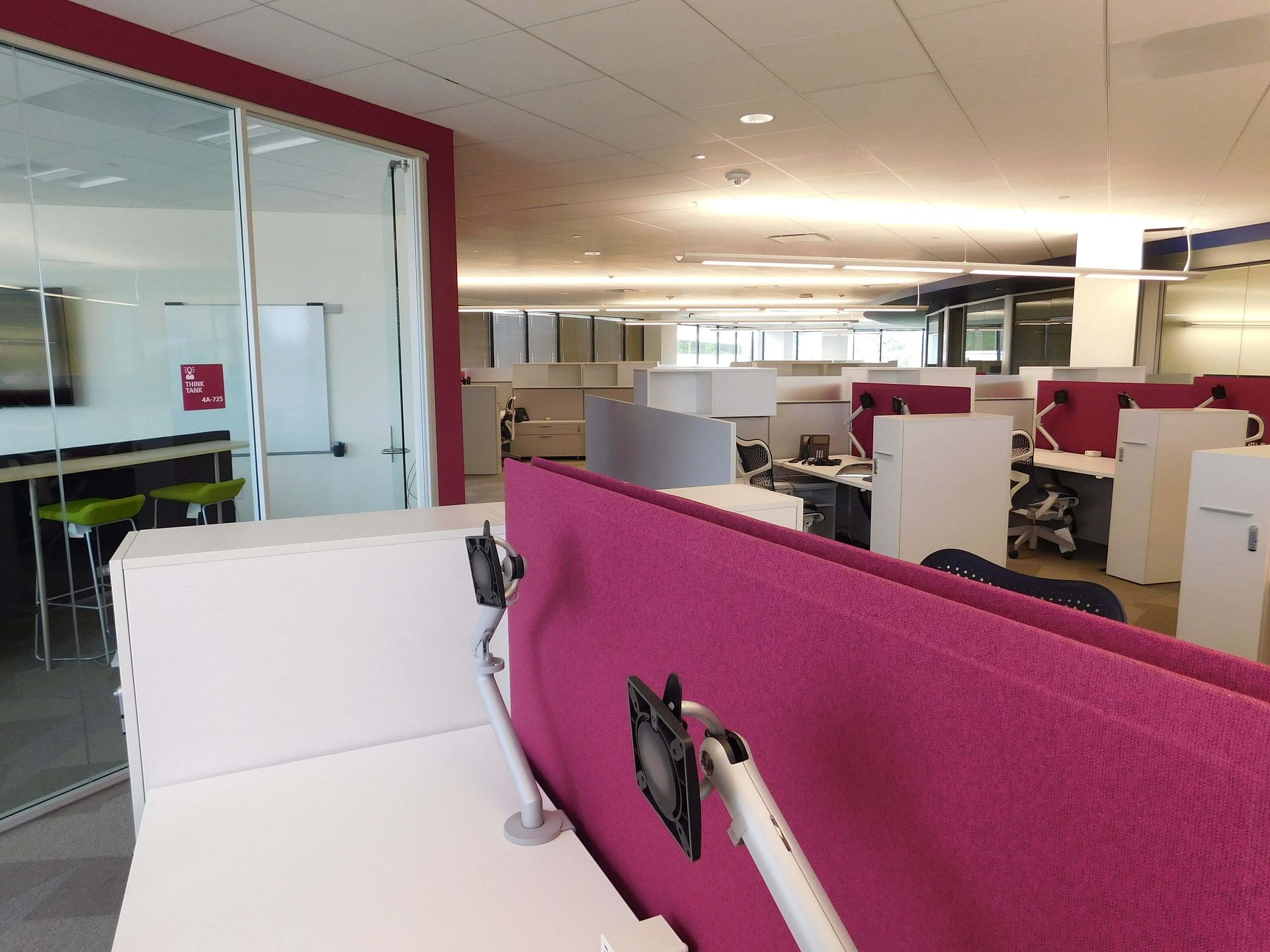 Modern office cubicles with pink partitions and glass-walled meeting rooms