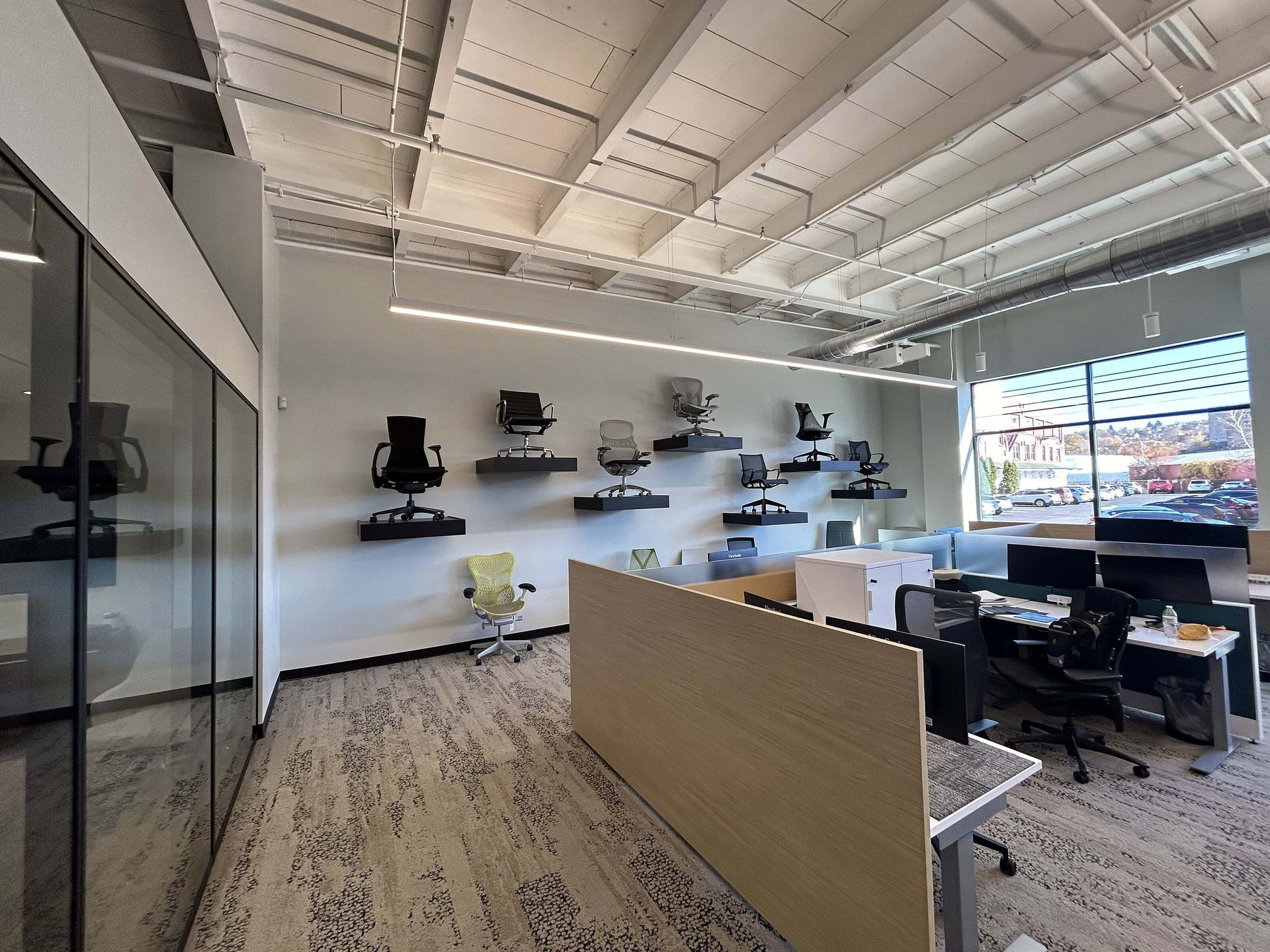 Modern office interior with desks, shelves, glass walls, and large windows