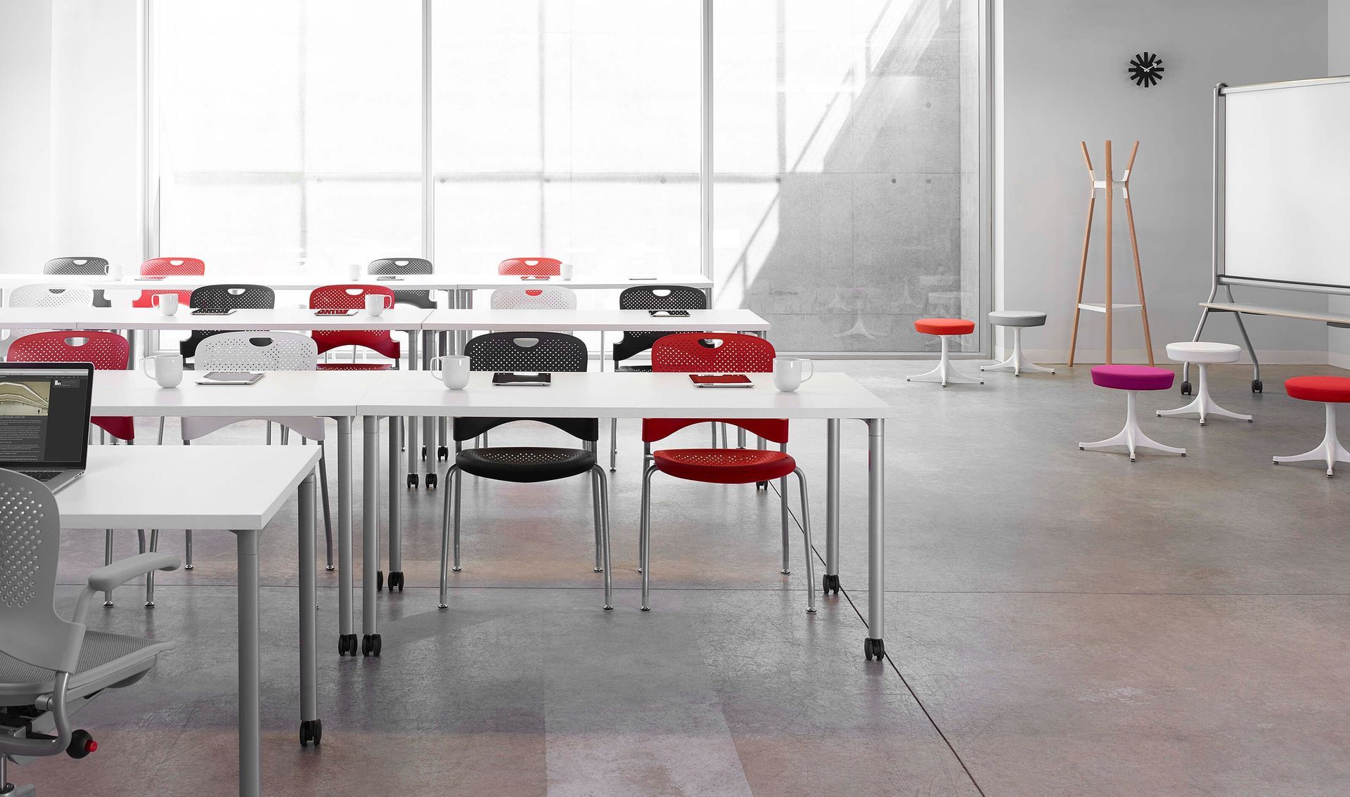 Modern bright classroom with white tables, red chairs, and a whiteboard in the background