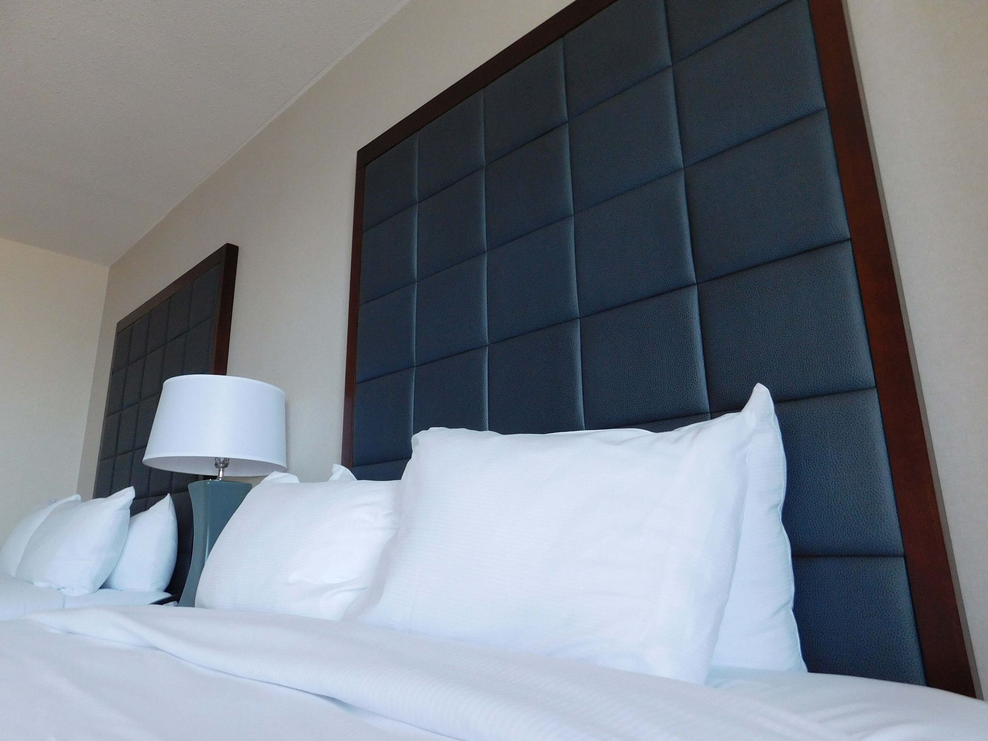 Modern bedroom headboard with white pillows and a bedside lamp