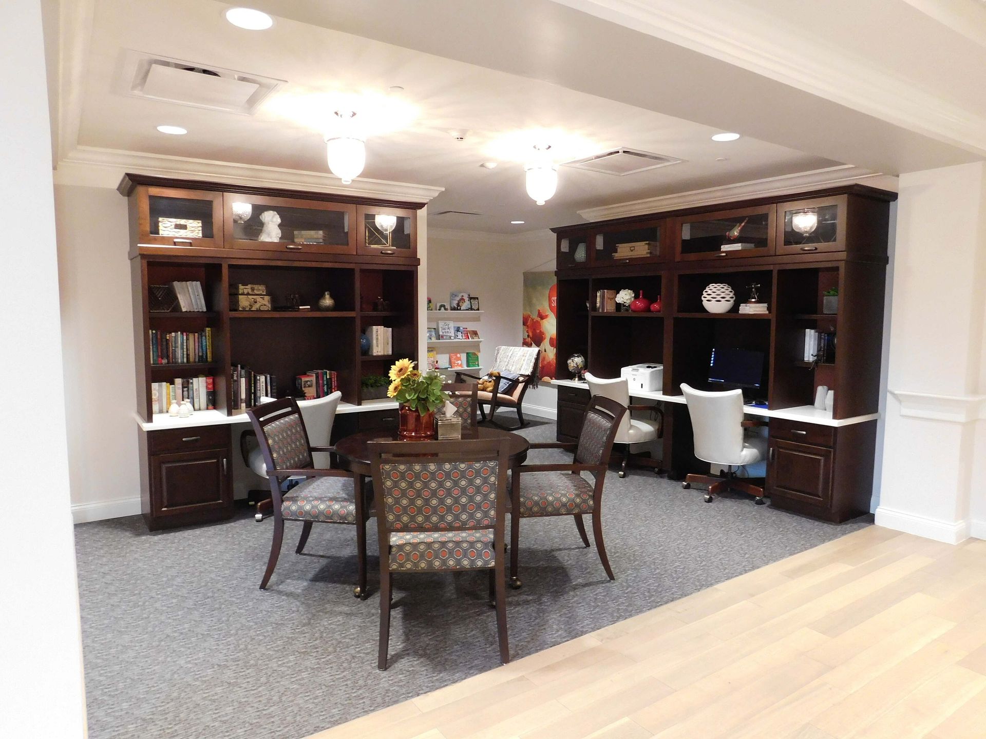 Office lounge with bookshelves, round table, and chairs under bright ceiling lights