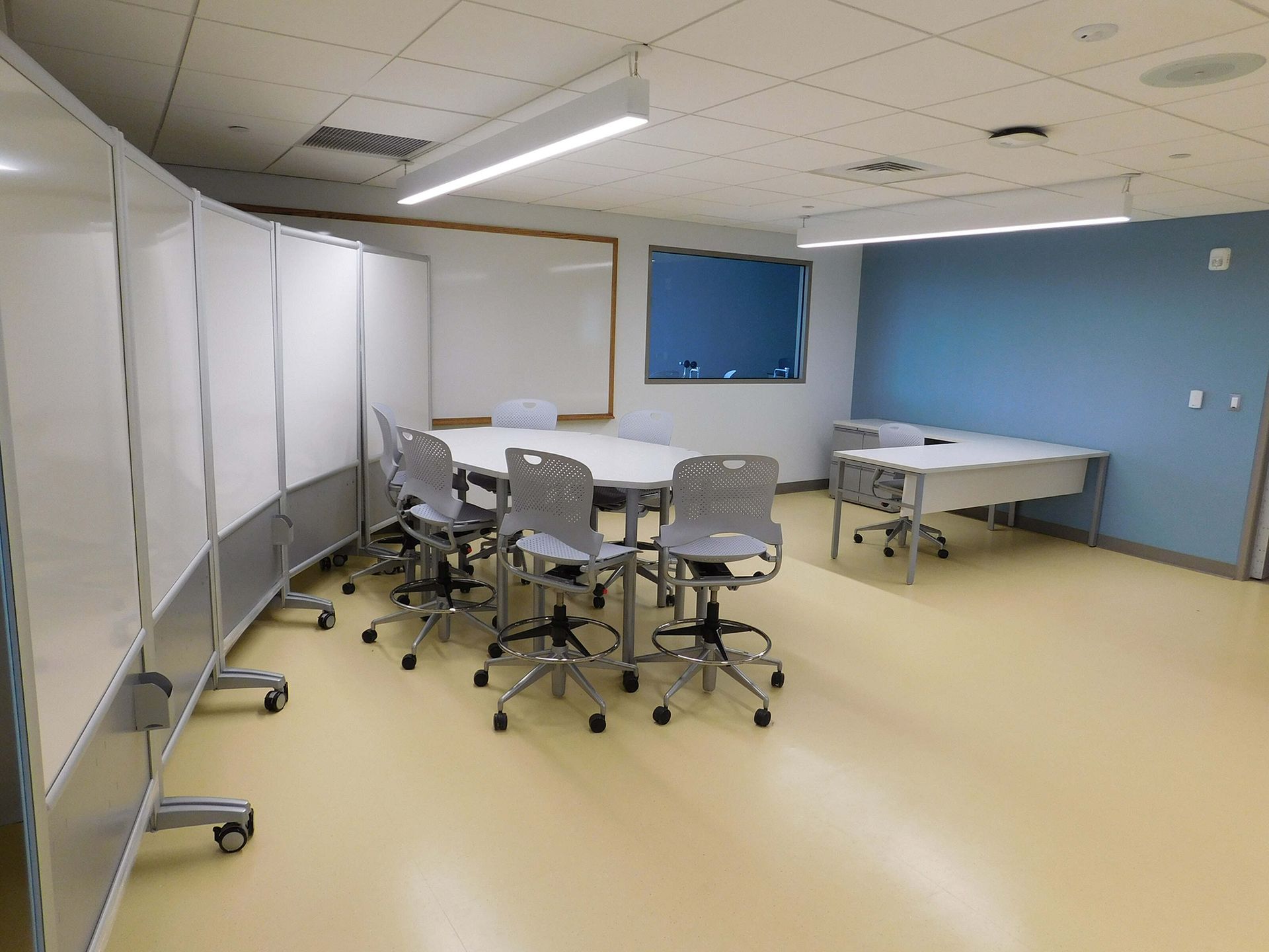 Empty modern meeting room with white folding partitions, gray chairs, and a blue accent wall.