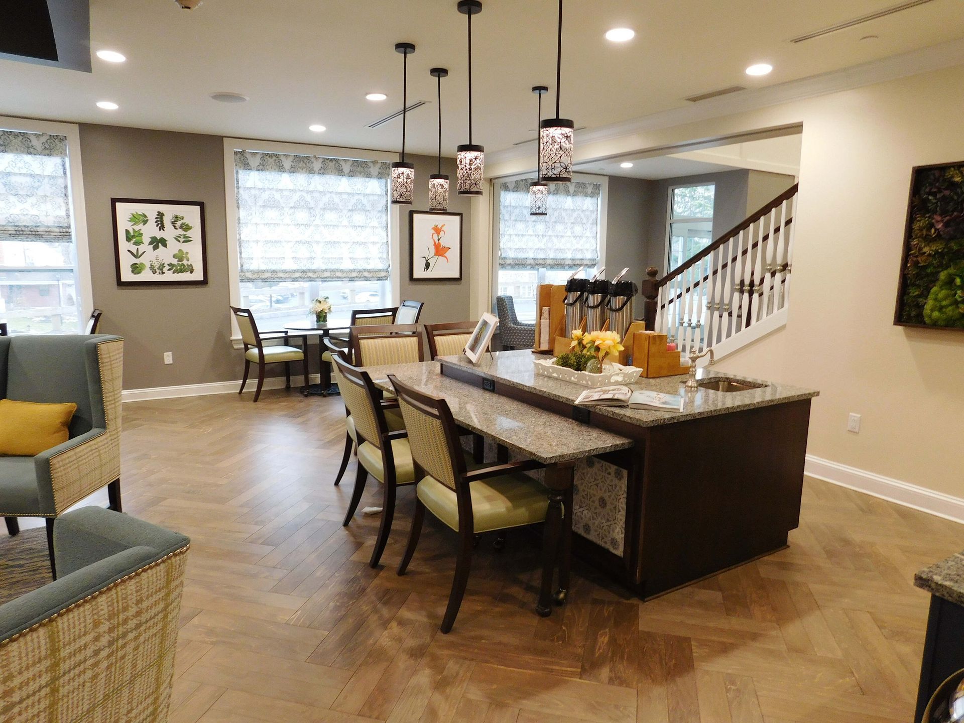 Open-plan dining room and kitchen with island, bar stools, staircase, and warm wood floors