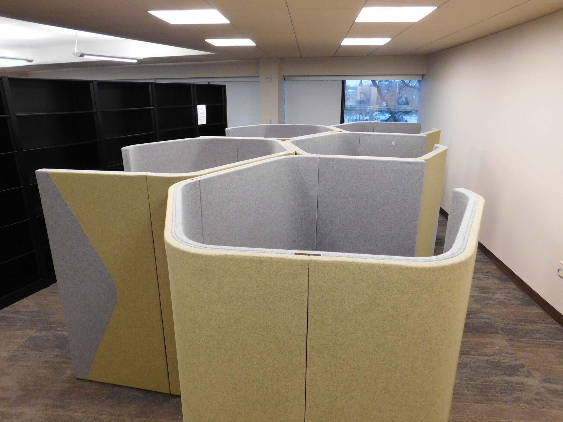 Office cubicles with beige and gray partitions in a fluorescent-lit room