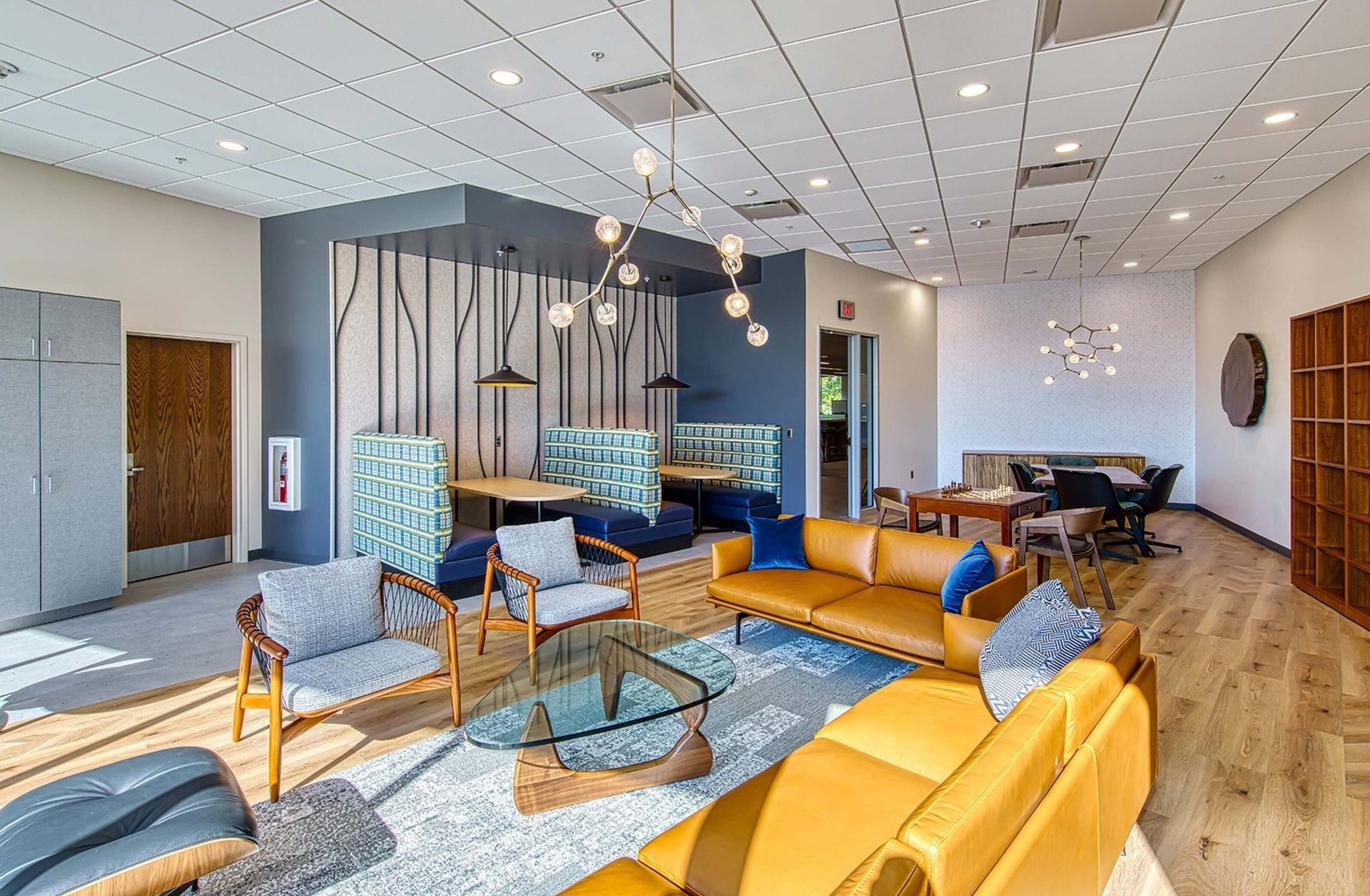 Modern lounge with mustard sofas, glass coffee table, pendant lights, and dining area in an open room