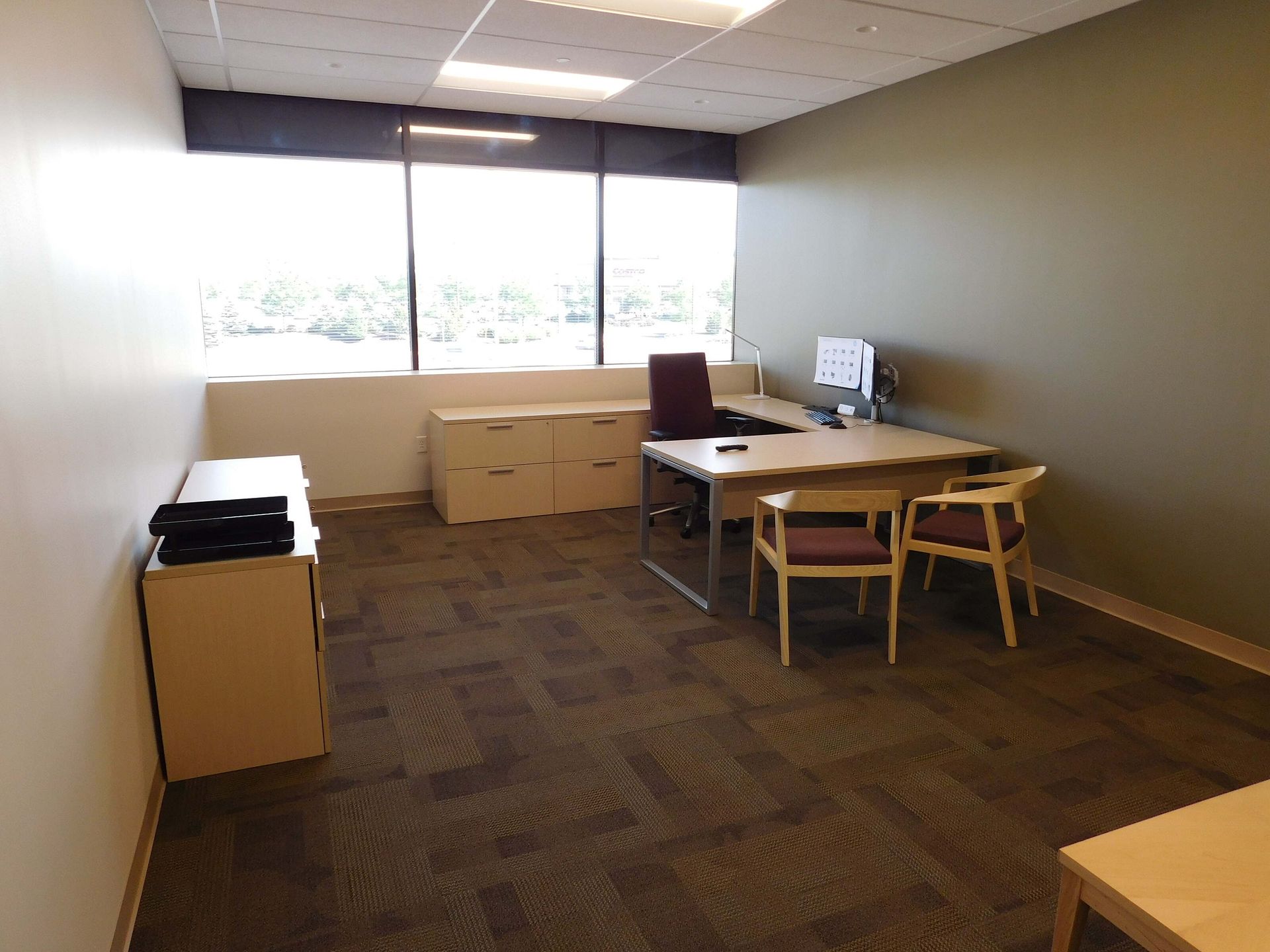 Empty office with desks, chairs, and cabinets near large windows