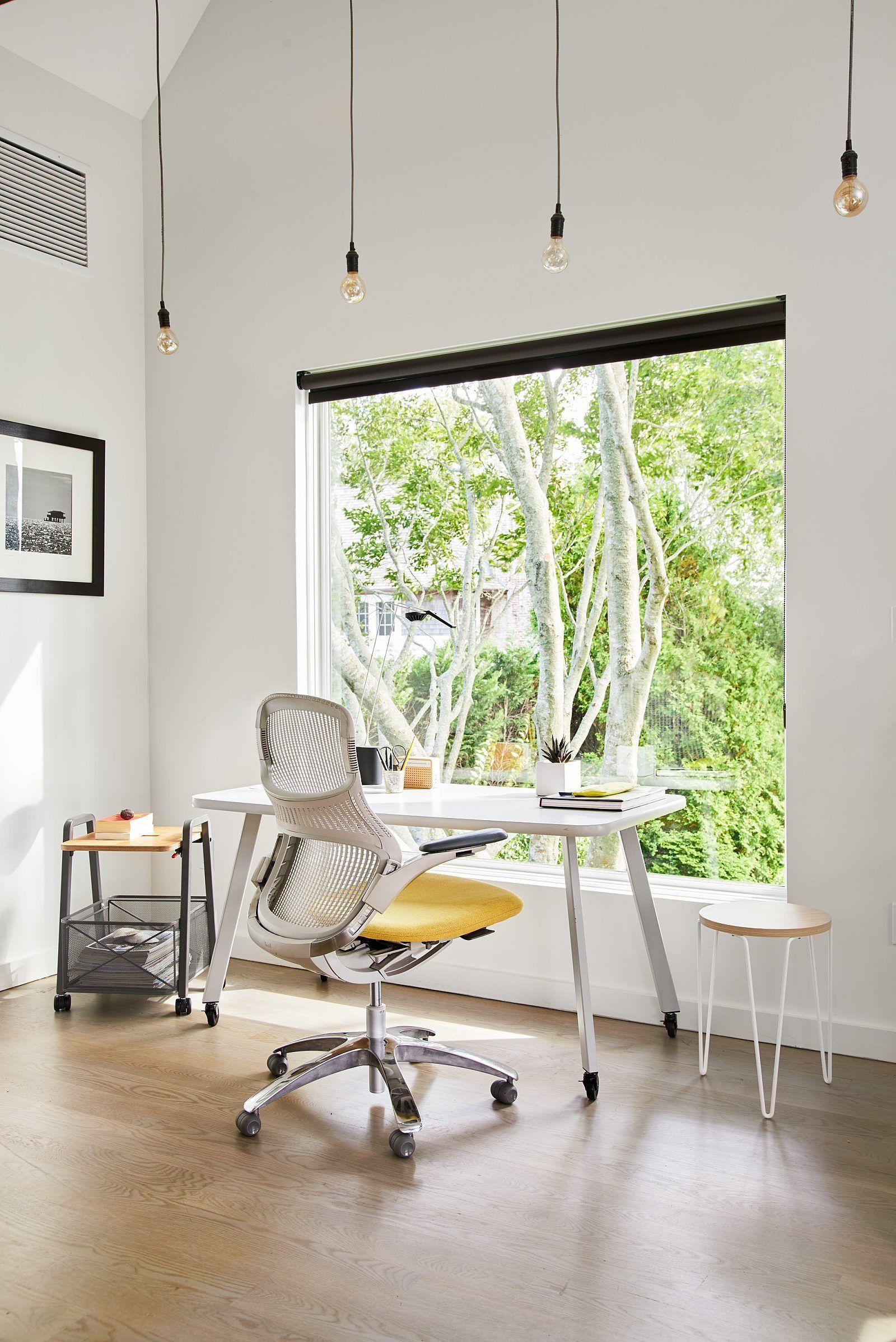 Bright modern office with a desk, rolling chair, and large window overlooking greenery