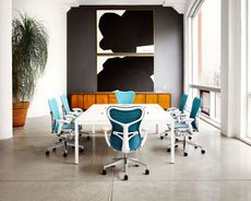 Modern conference room with white table and teal swivel chairs by large windows