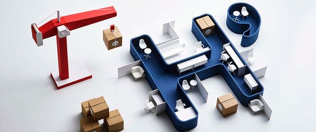 Miniature construction scene with a red crane, blue machinery, and small cardboard boxes on a white surface