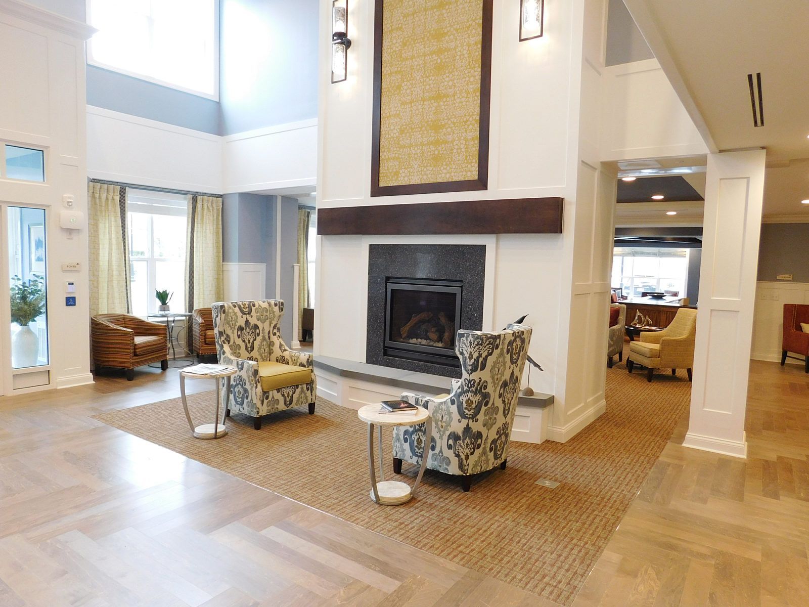 Spacious living room with a stone fireplace, wicker chairs, and light wood floors in a bright modern home