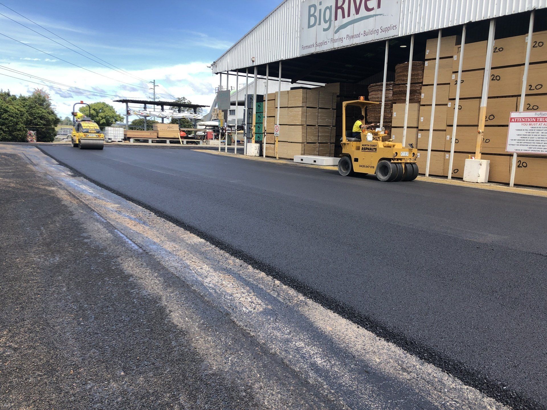 A forklift is driving down a road in front of a building that says big river.