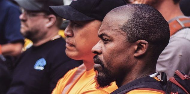 A man with a beard is sitting in a crowd of people.