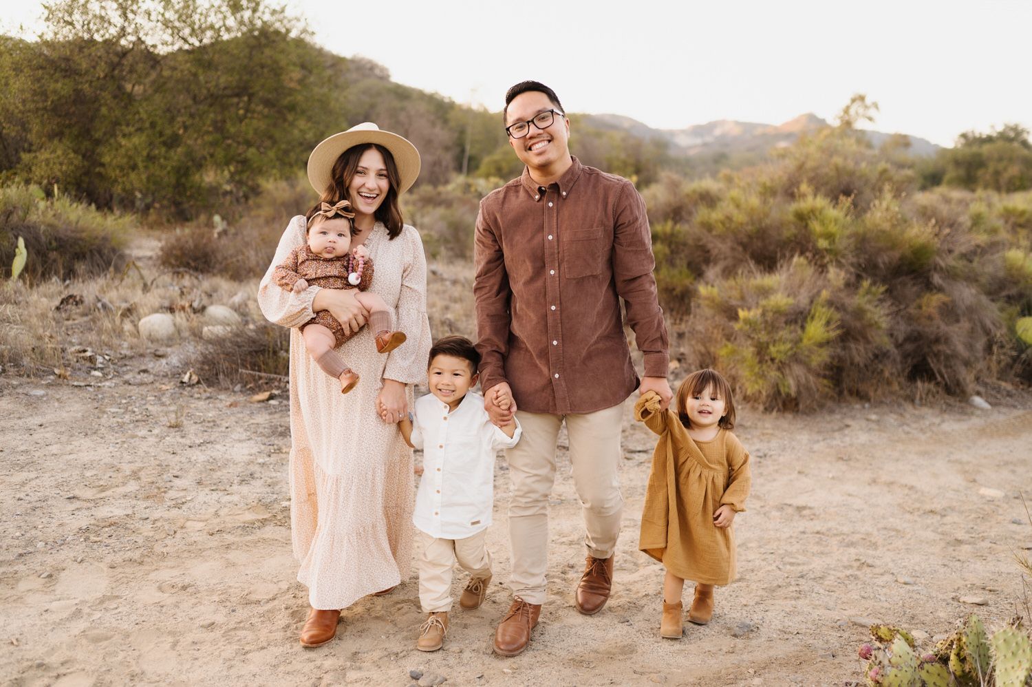 A family is posing for a picture in the desert while holding hands.