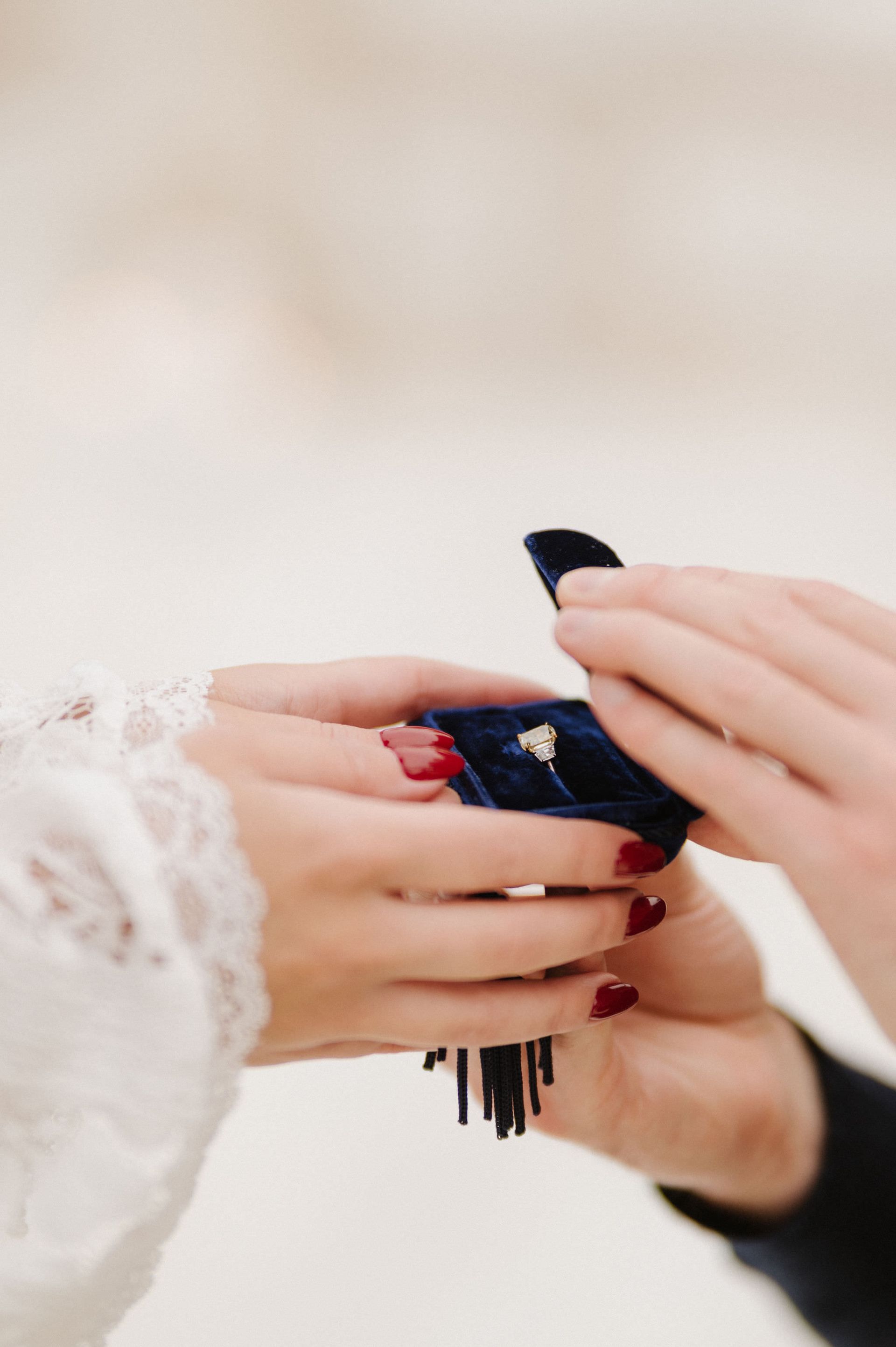 Hands passing a navy tassel bag with red and gold details at a proposal with The Yes Girls