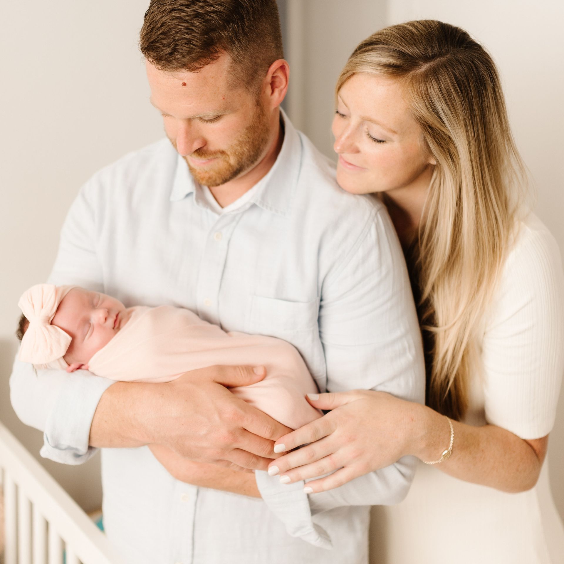 A man and woman are holding a newborn baby in their arms for an in home newborn photos in Orange County