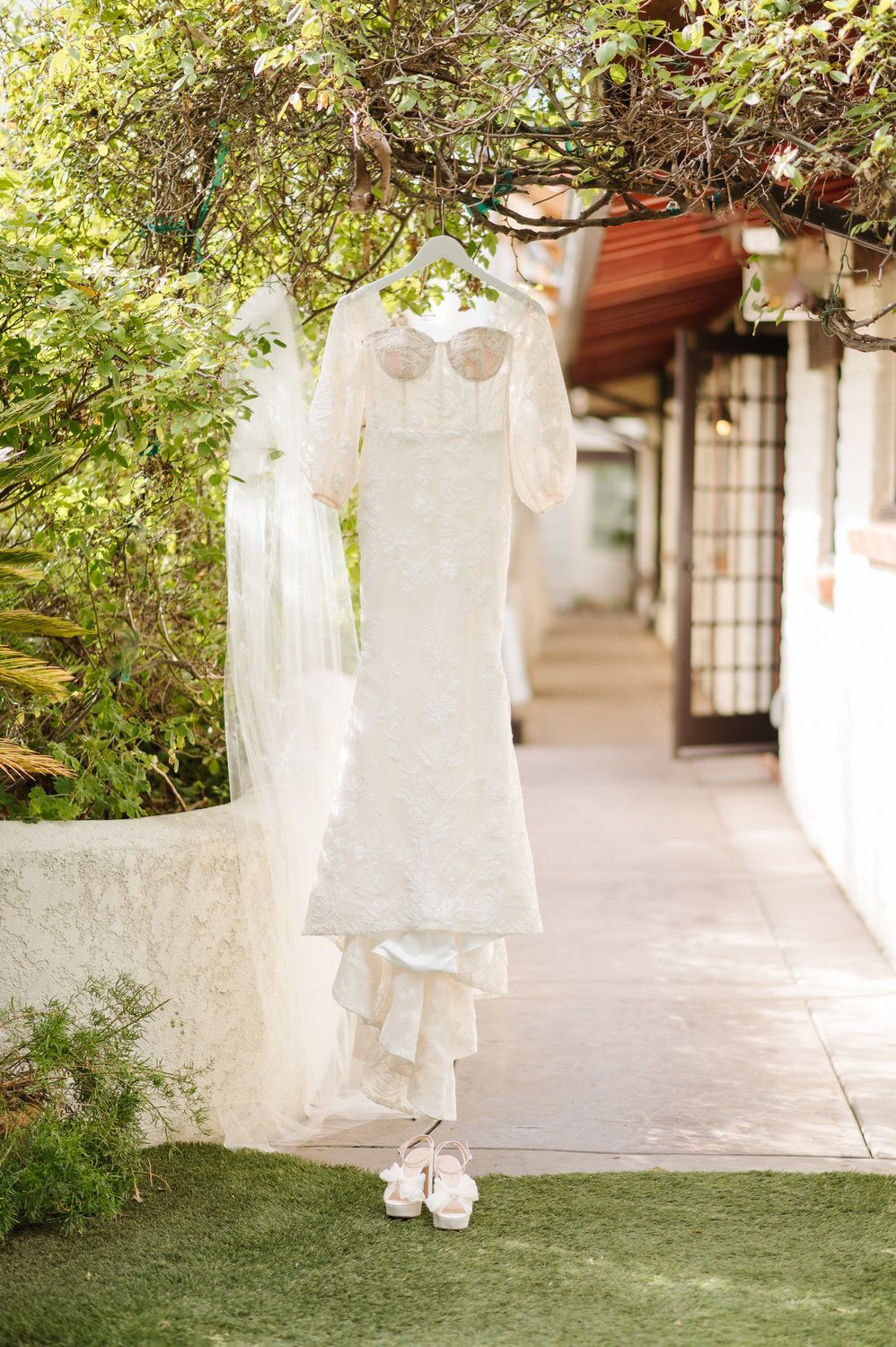 A wedding dress and veil are hanging from a tree.