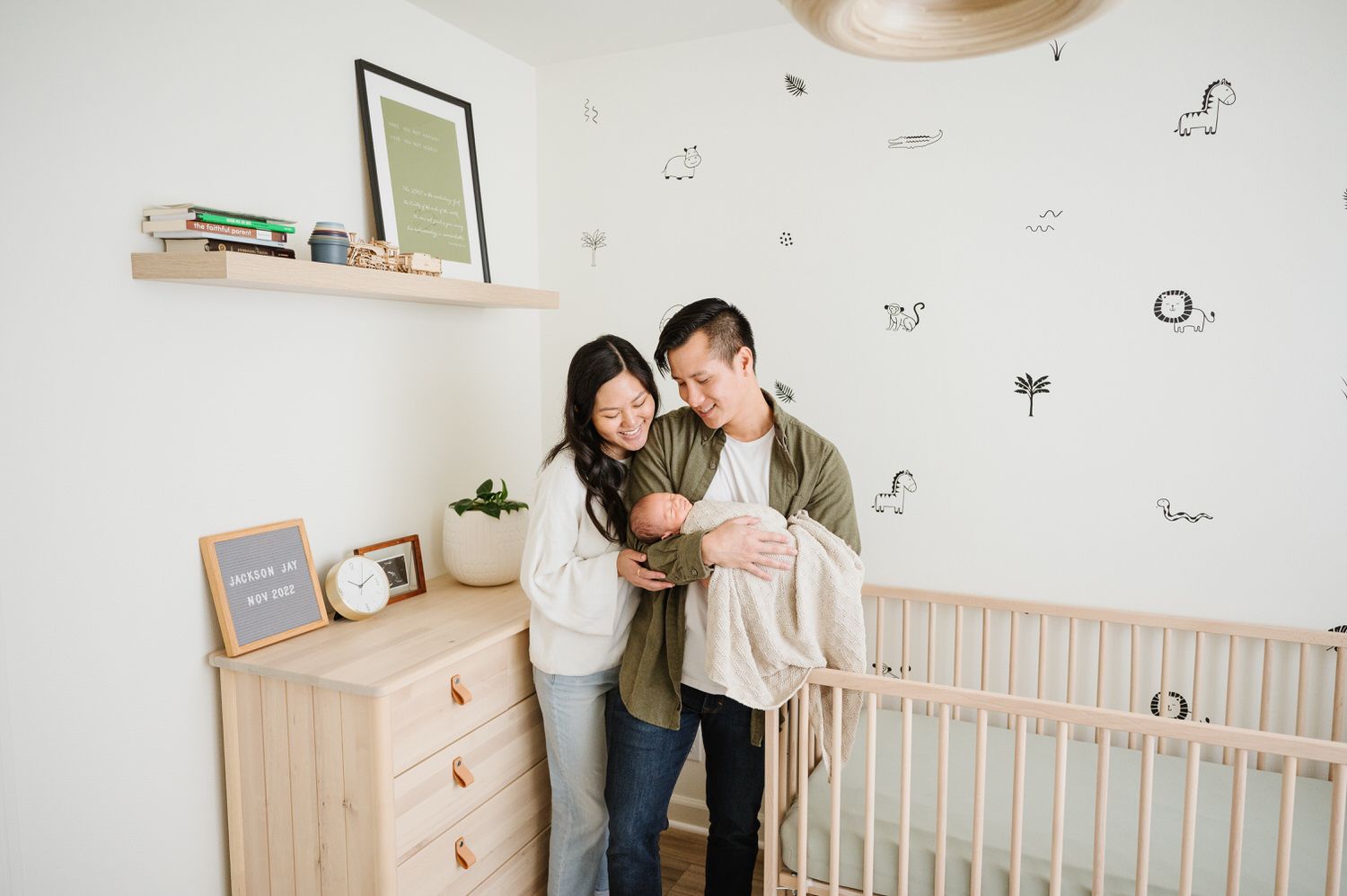 A man and woman are holding a newborn baby in a nursery for an in home newborn photo in Orange County.