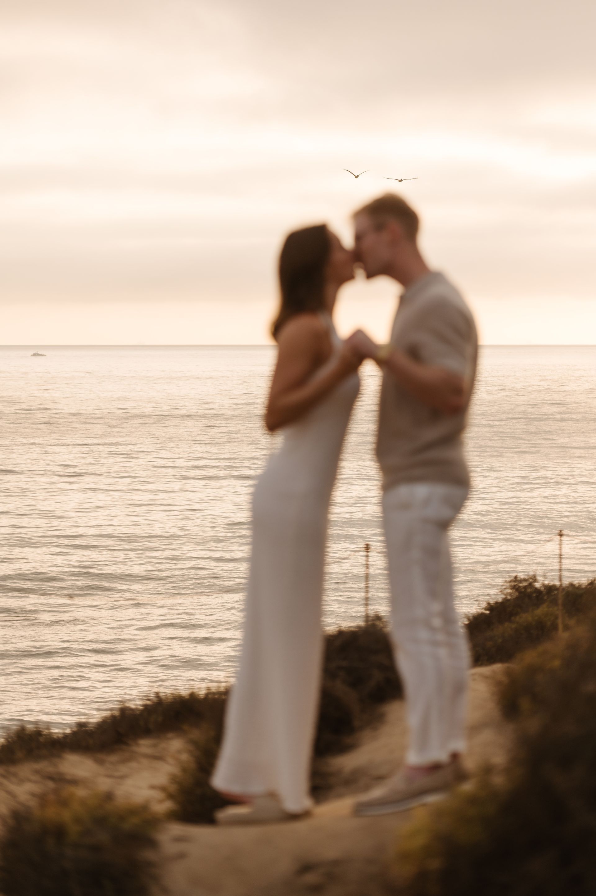 Couple standing close together at sunset by the sea for a proposal with The Yes Girls