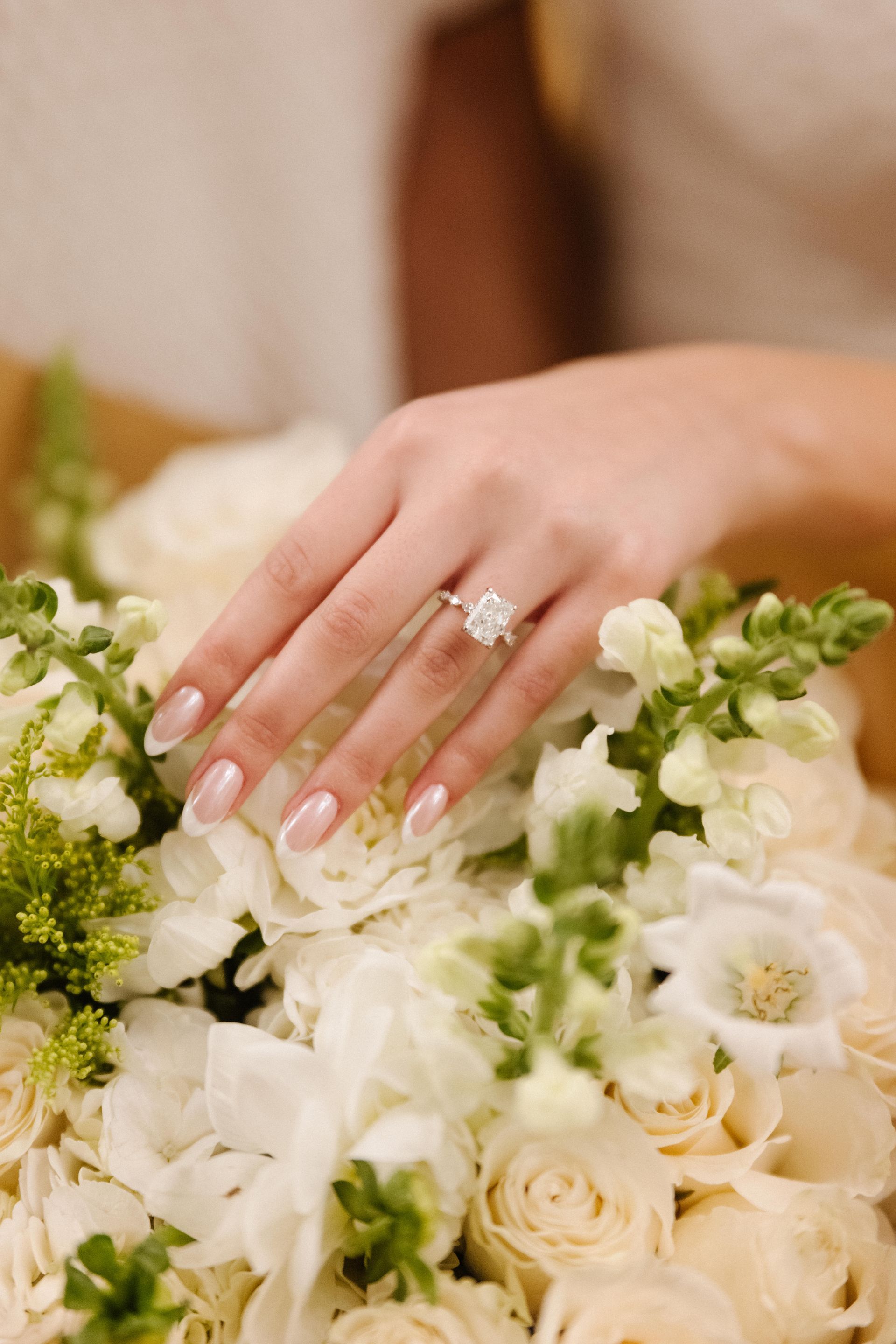 Hand with diamond ring resting on white and green floral bouquet at Lido House