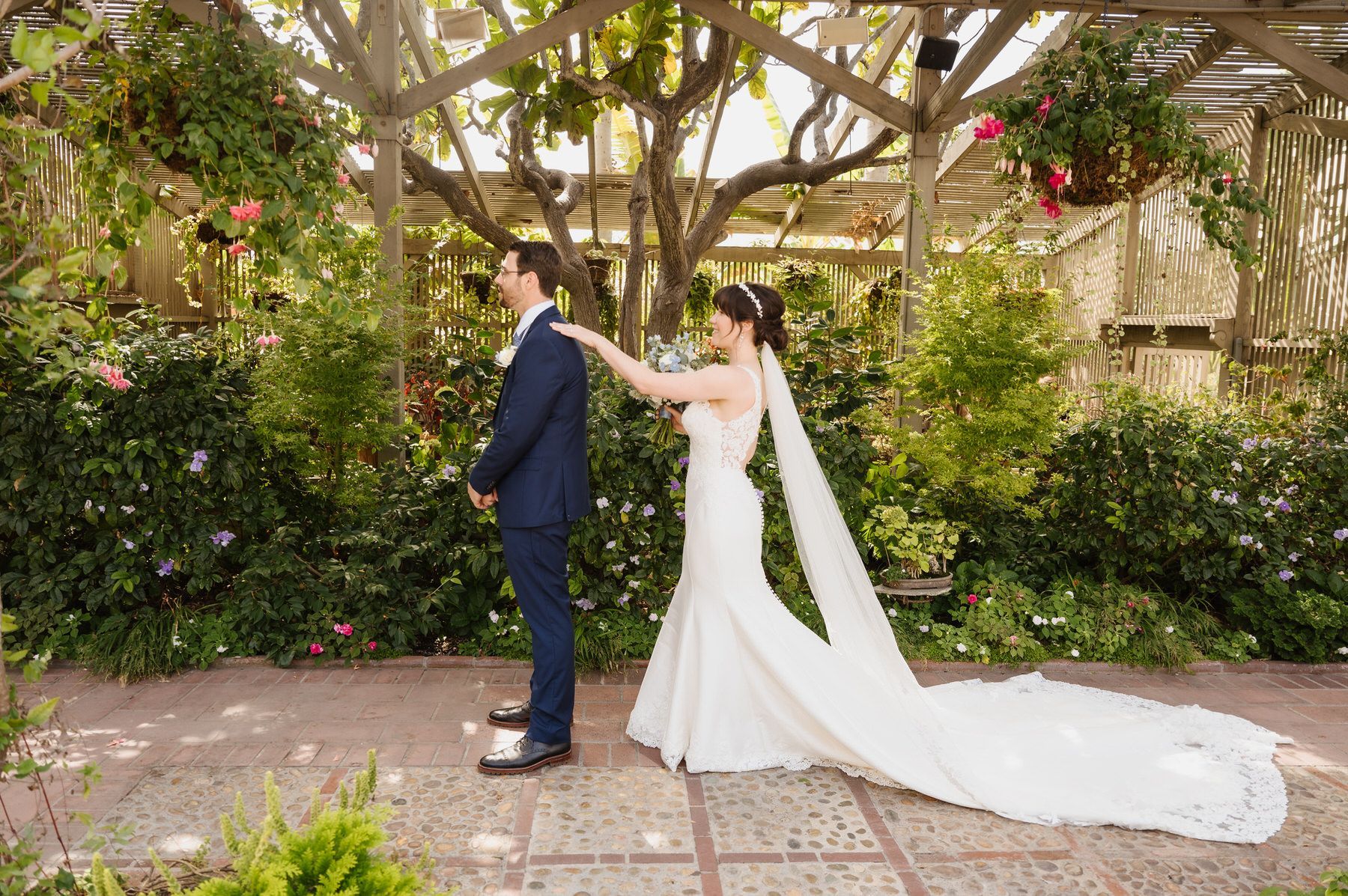 A bride and groom are standing next to each other at Sherman garden seeing each other for the first time on their wedding day