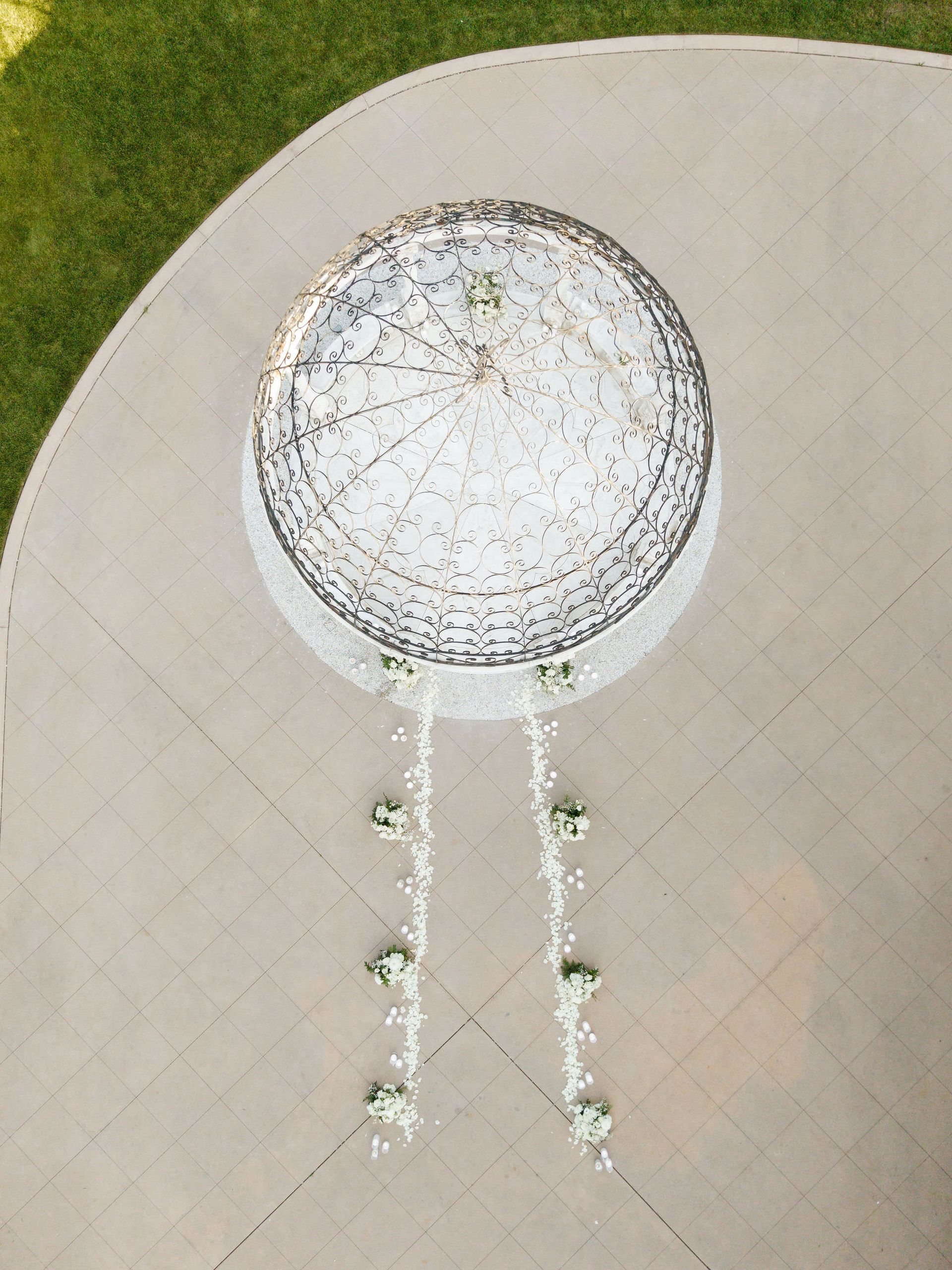 Overhead view of a circular fountain or sculpture with two narrow paths or streams extending downward on a paved surface