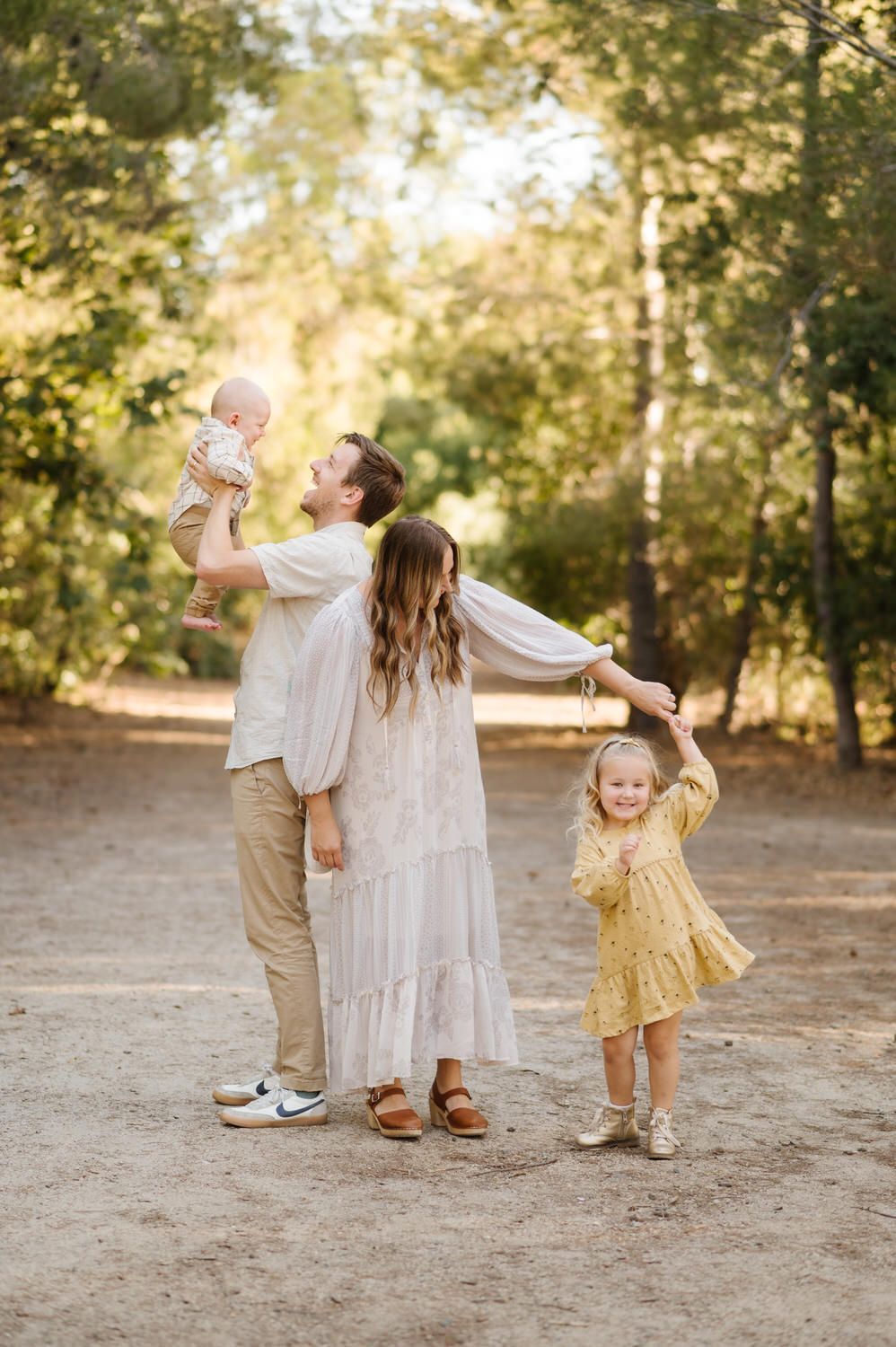 A family is standing next to each other in the woods holding hands.