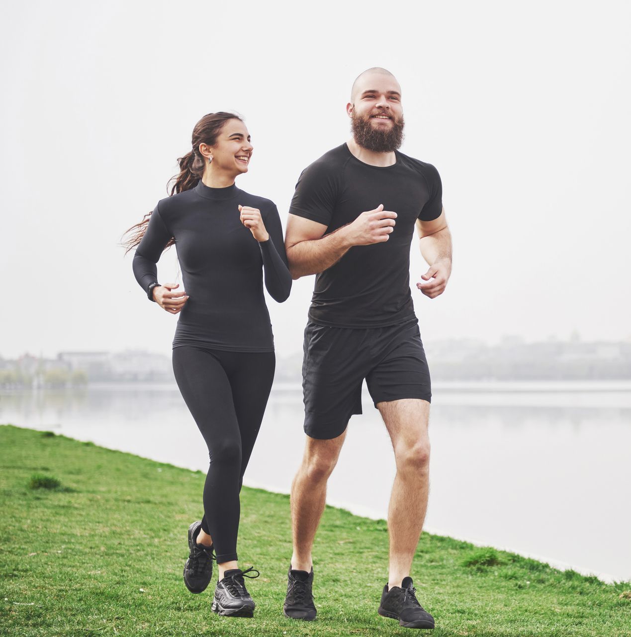 A man and a woman are running next to a body of water.