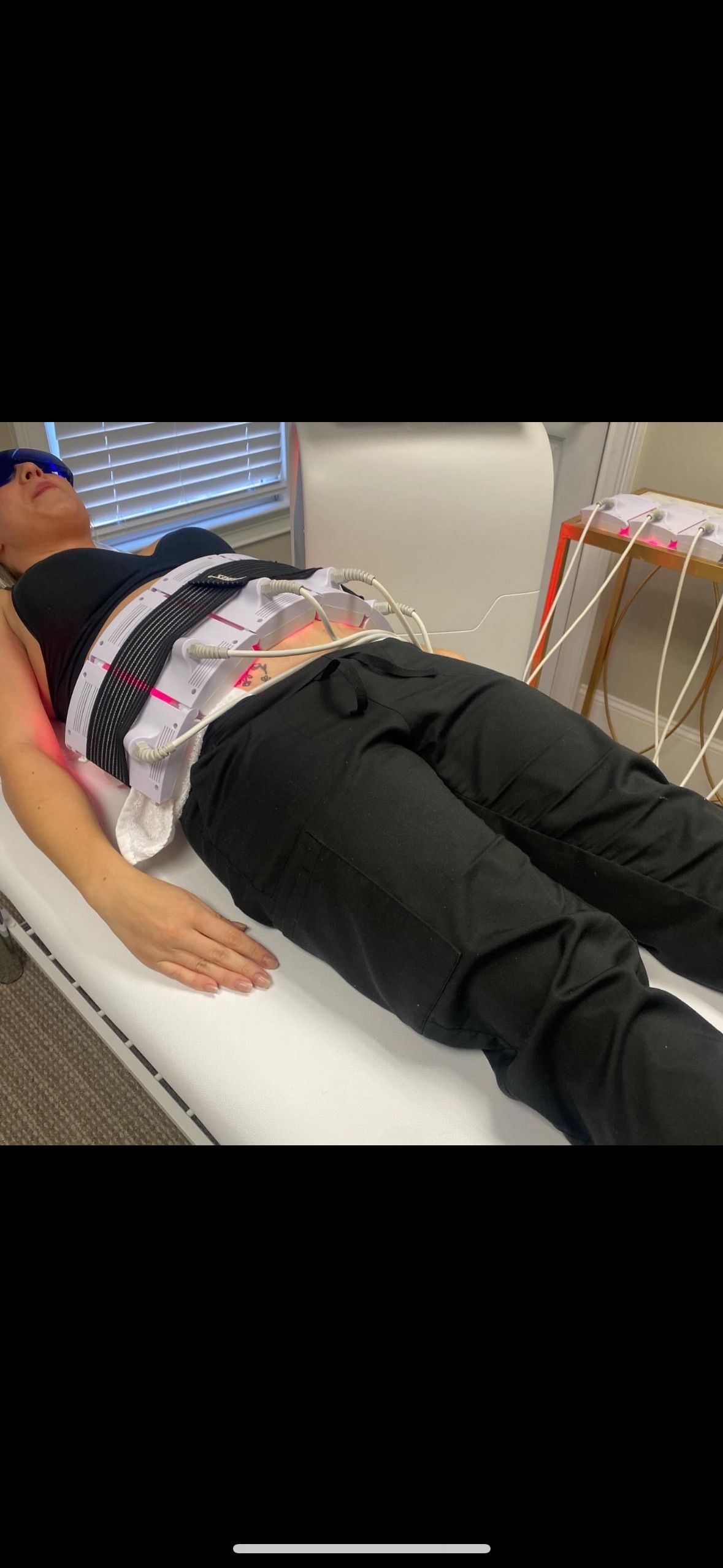 A woman is laying on a bed with a machine on her stomach.