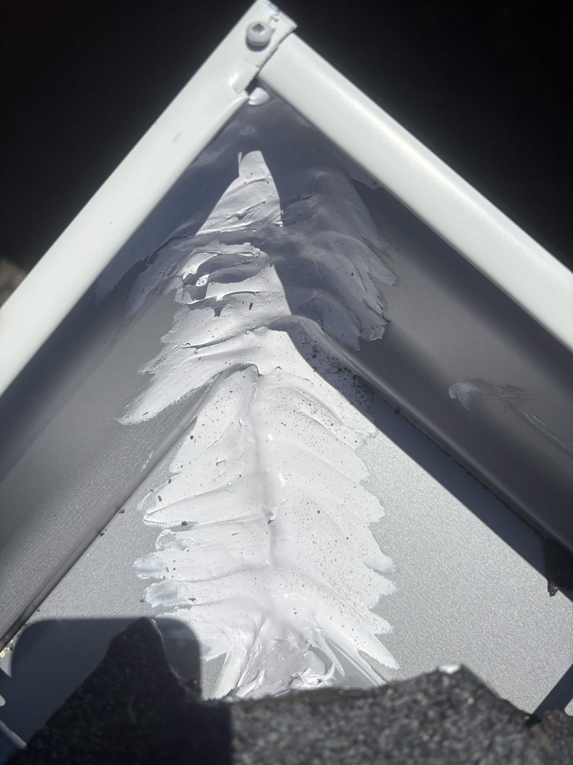 Close-up of a white sealant bead along a gutter joint