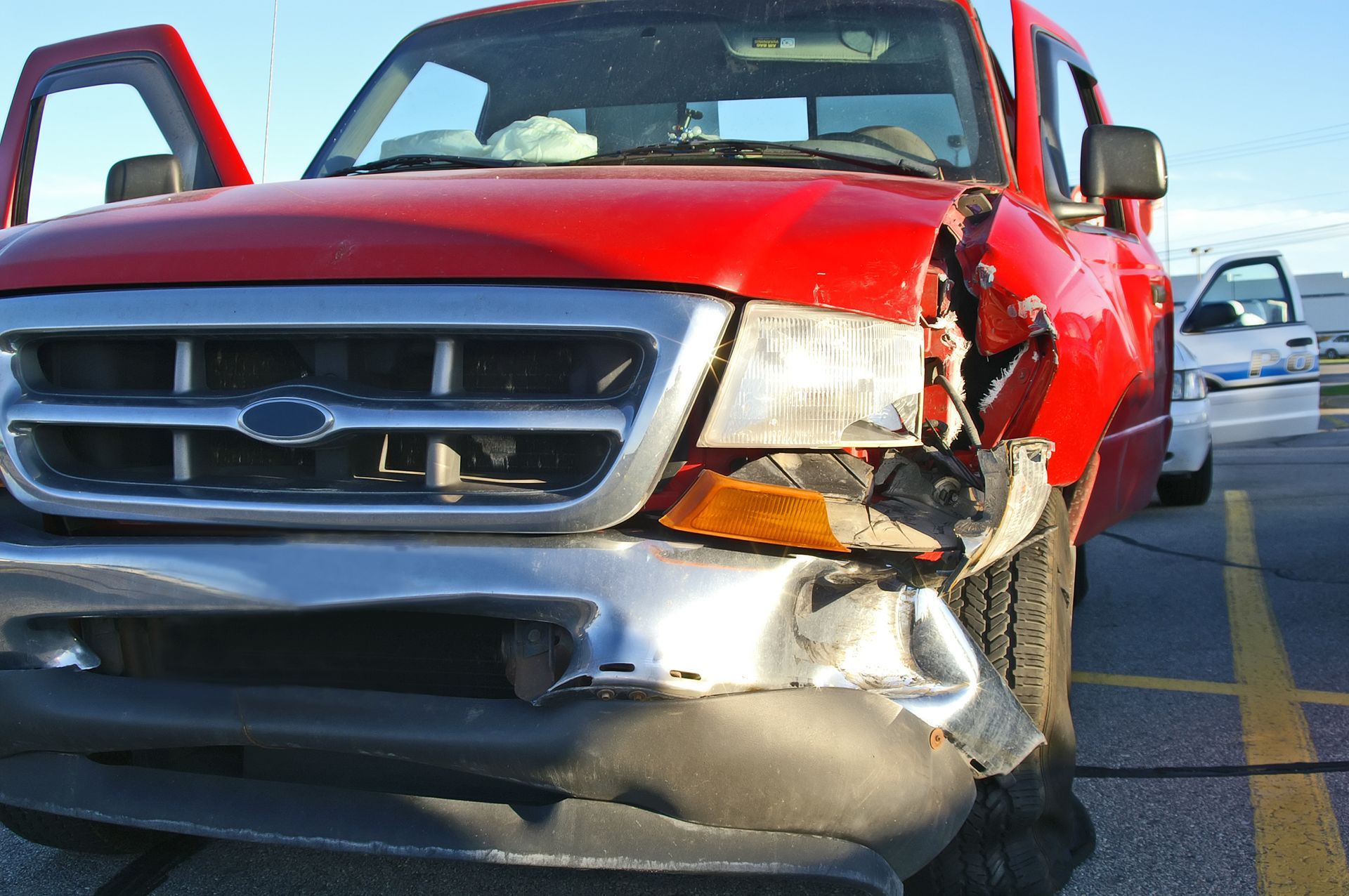A damaged red ford truck is parked in a parking lot