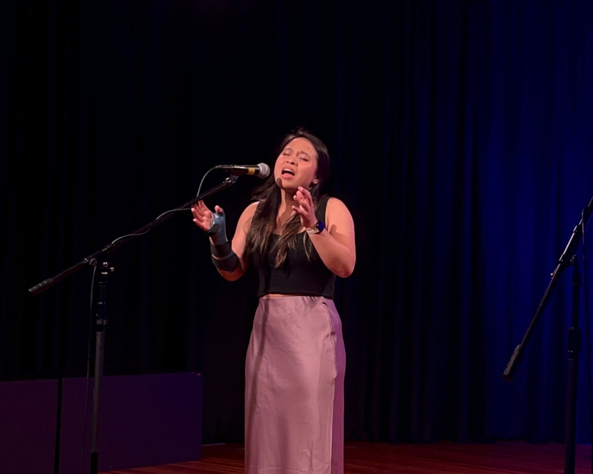 A young woman singing at a microphone
