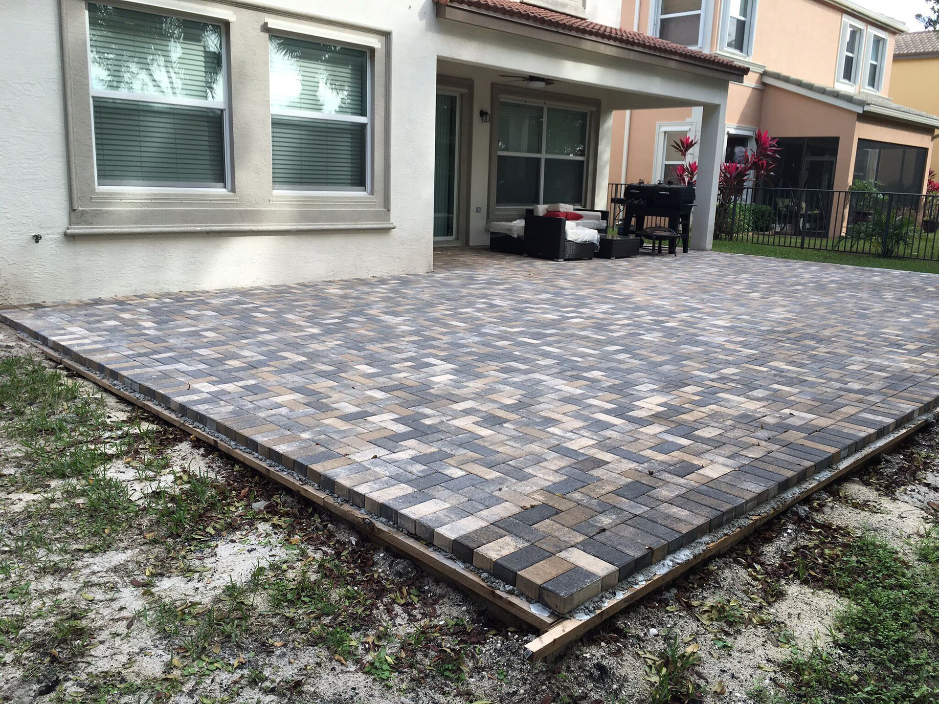 A brick patio is being built in front of a house.