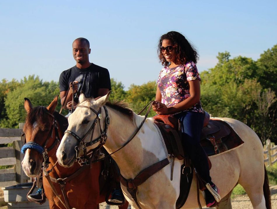 A girl is standing next to a brown horse in the woods