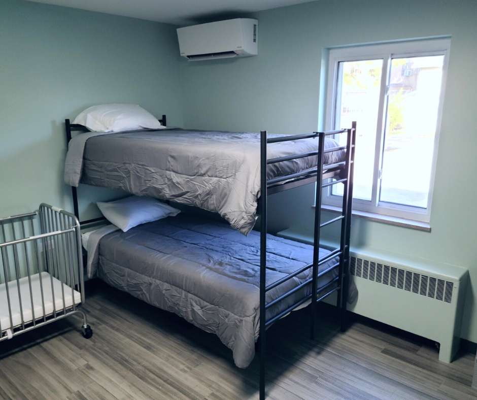 Bunk beds with gray bedding in a room with light blue walls and a small crib.