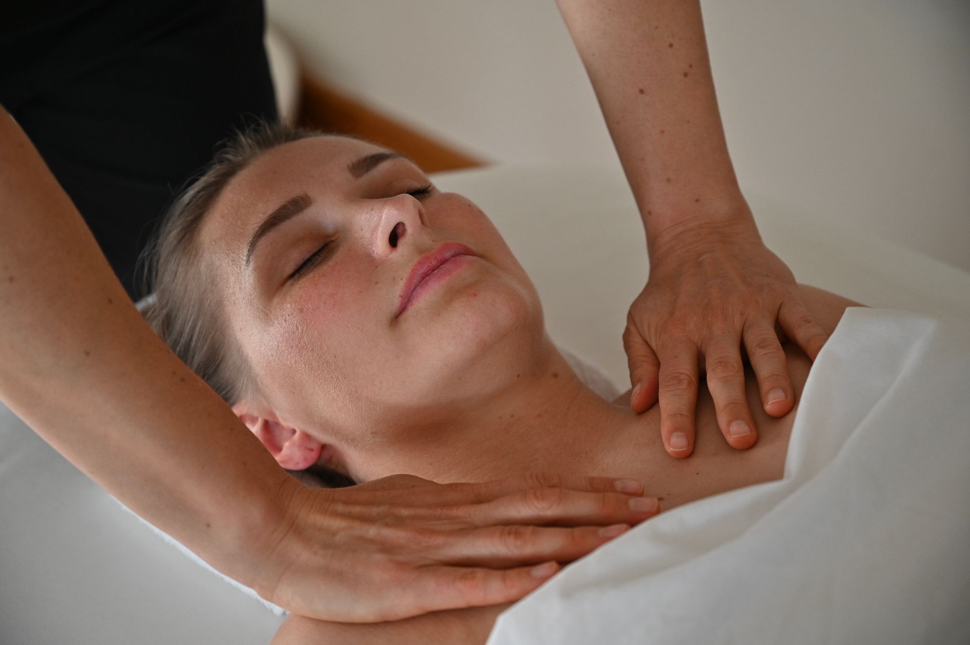 Frau erhält eine Massage an Nacken und Schultern.